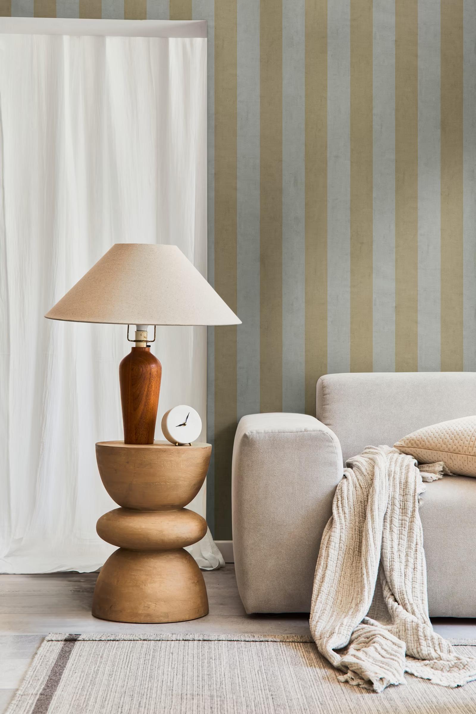 Sage Stripe wallpaper beside a table lamp and bouclé sofa