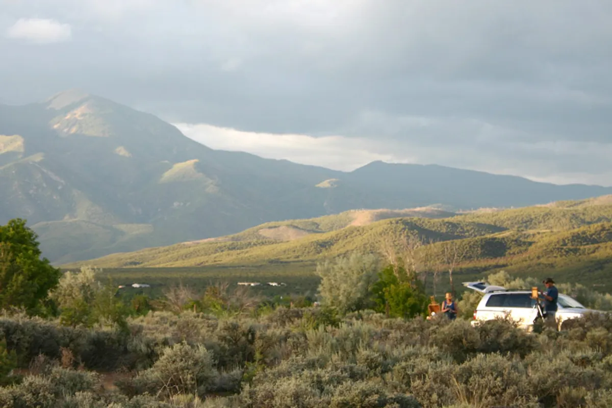 painting at an easle in the mountains