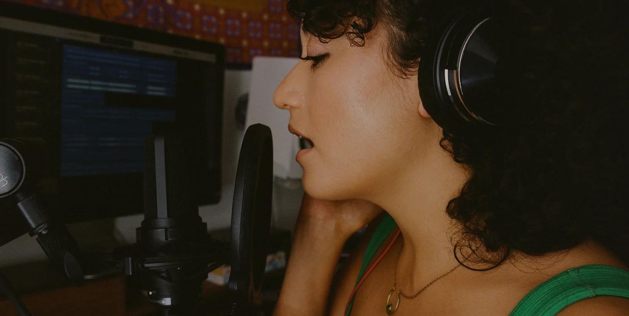 Wide cinematic hero image — music production studio with producer working on sample library