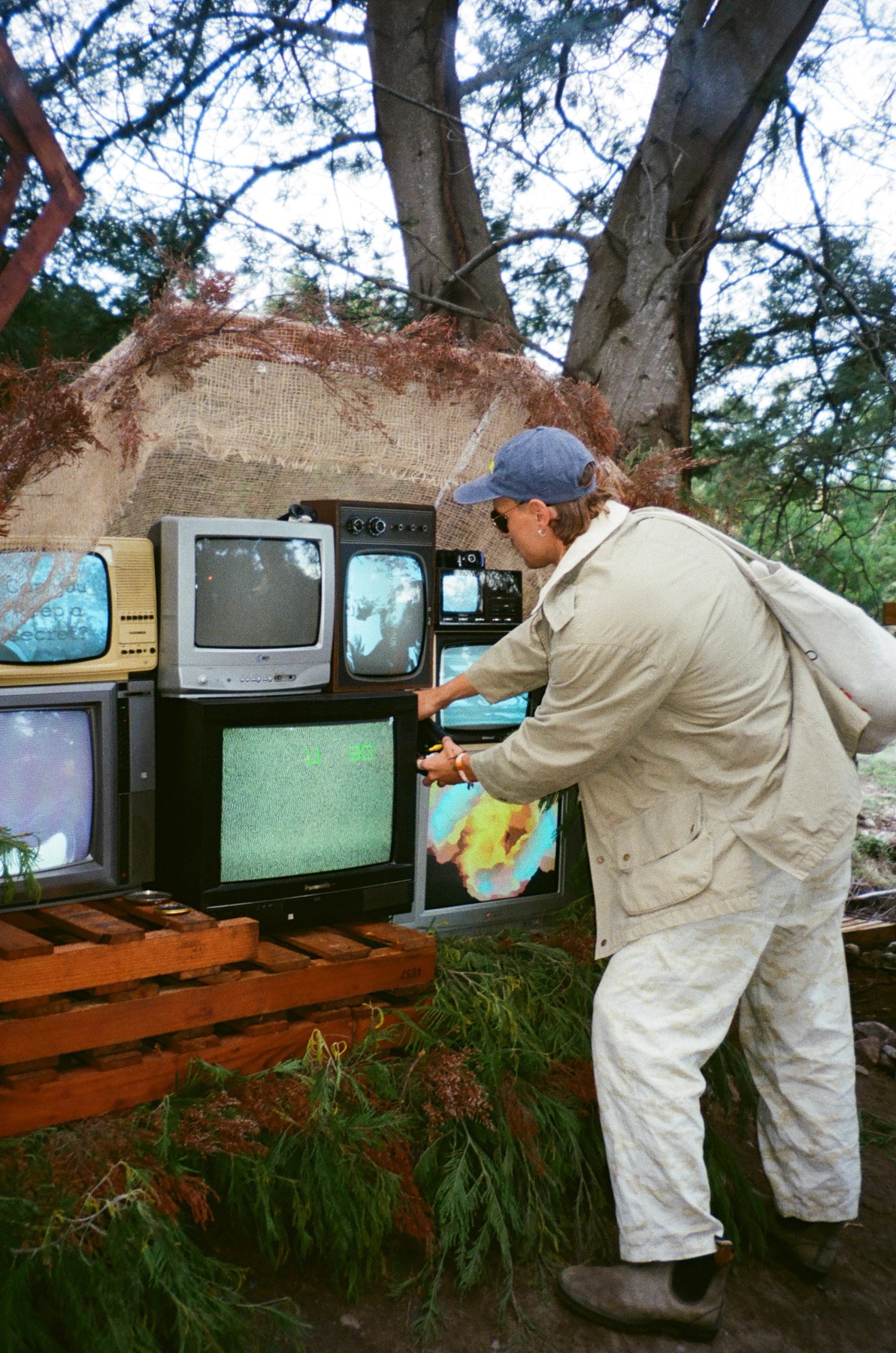 Artist setting up CRT televisions displaying generative visuals at an outdoor installation