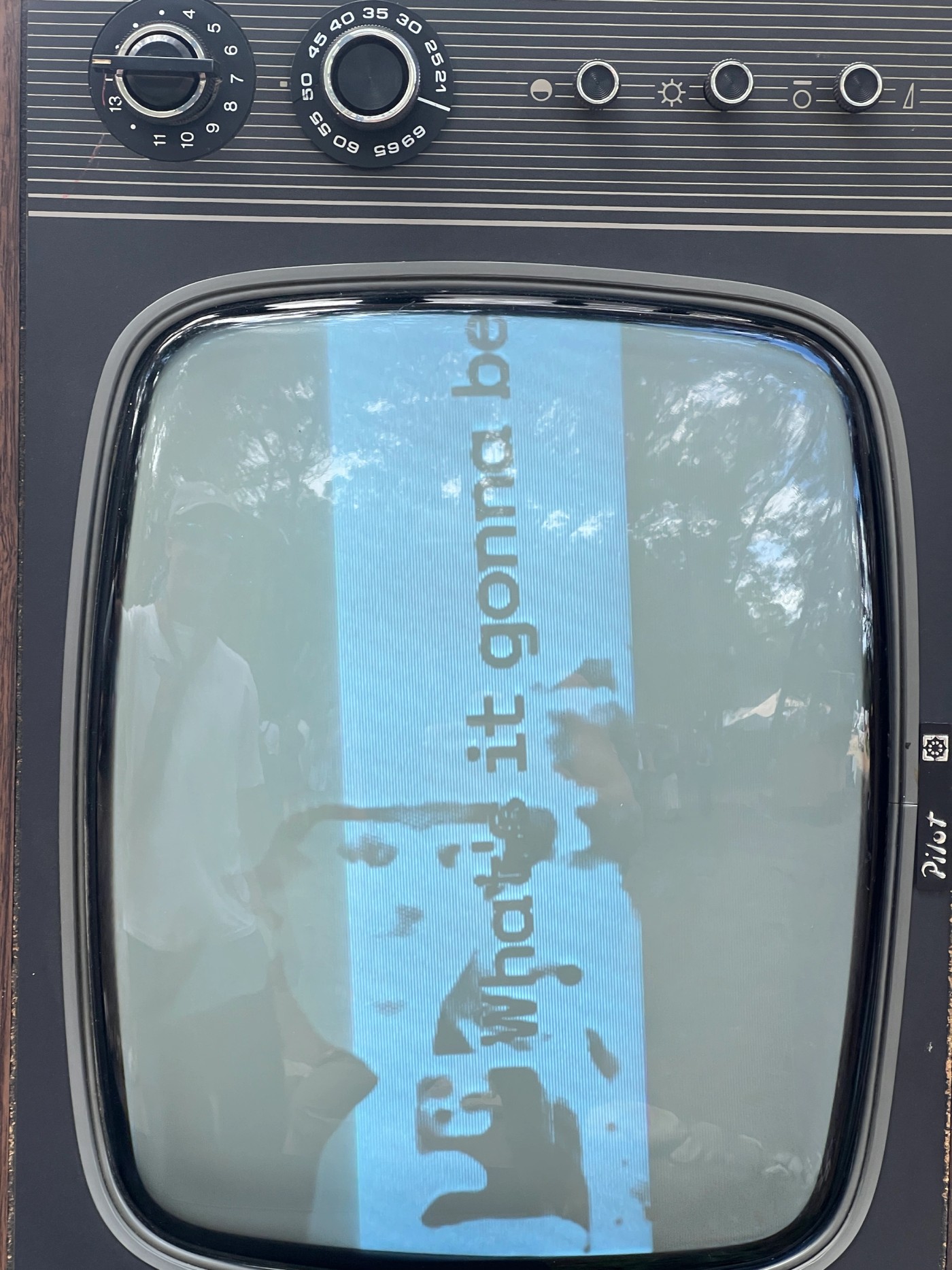 Close-up of a vintage CRT television screen displaying text and abstract visuals