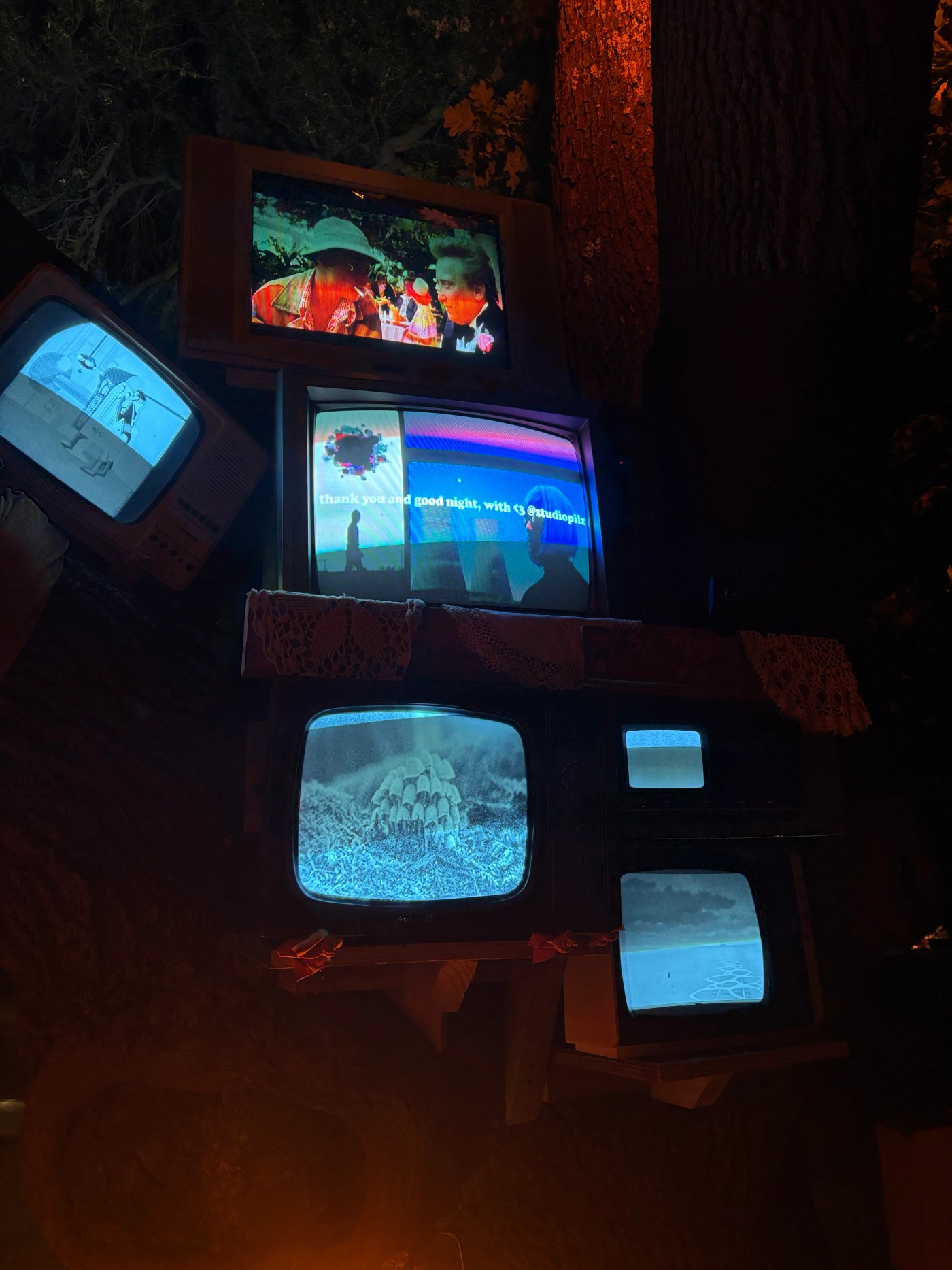 CRT TVs stacked in a tree at night