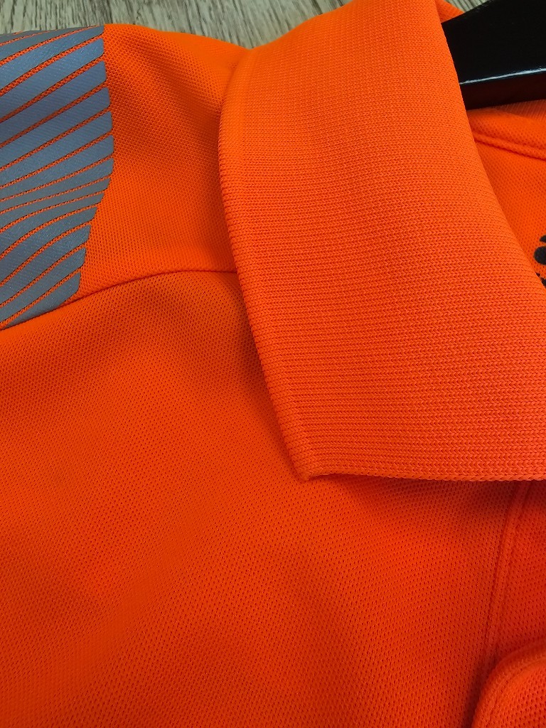Hi-vis polo shirt showing diagonal shoulder retroreflective tape passing from front to back per EN ISO 20471 design requirements