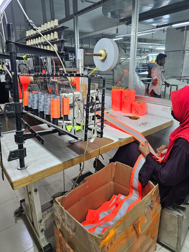 Reflective tape being applied to hi-vis workwear on a Bangladesh production line
