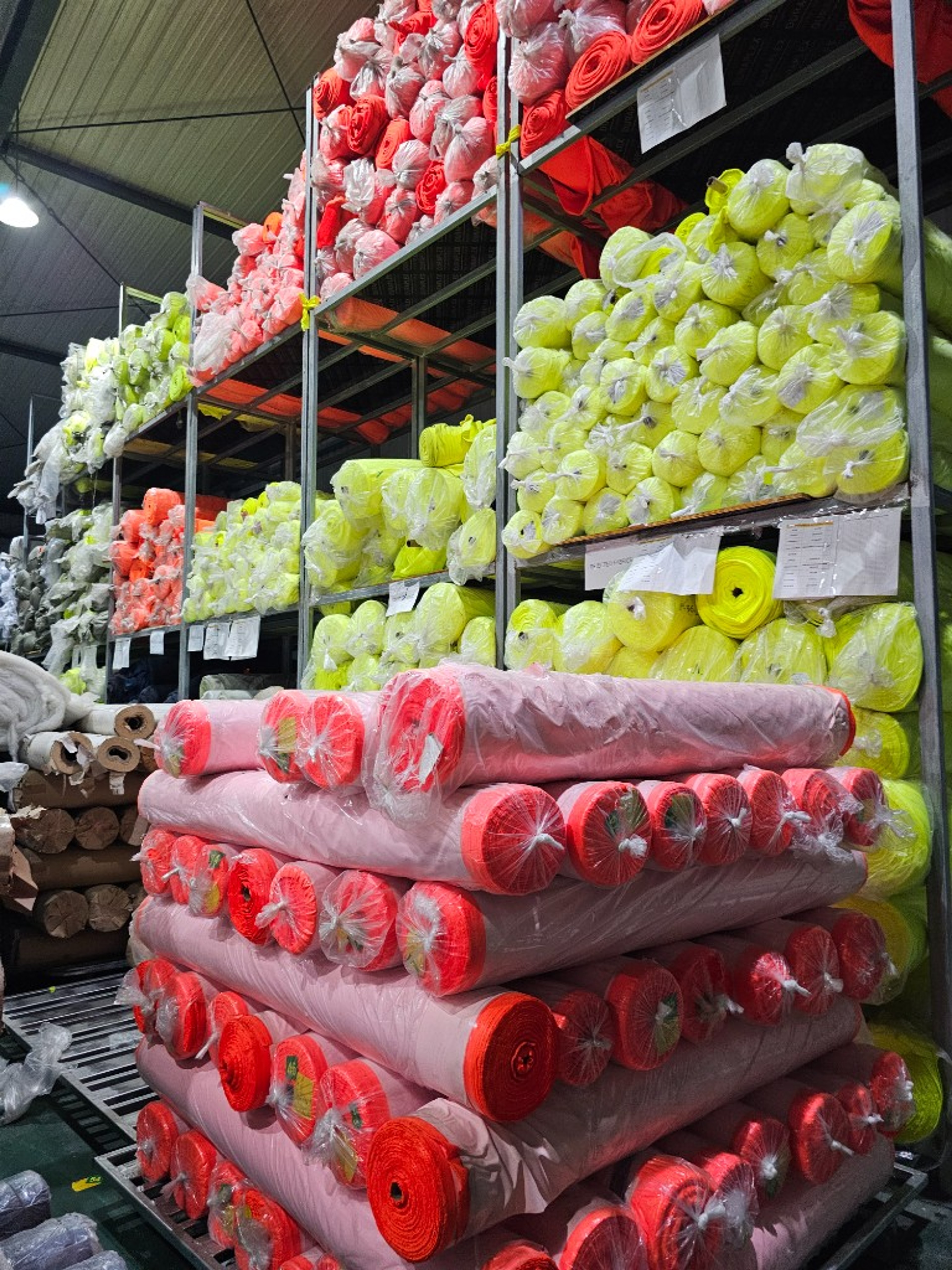 Stacks of fluorescent hi-vis fabric in yellow and orange, ready for cutting