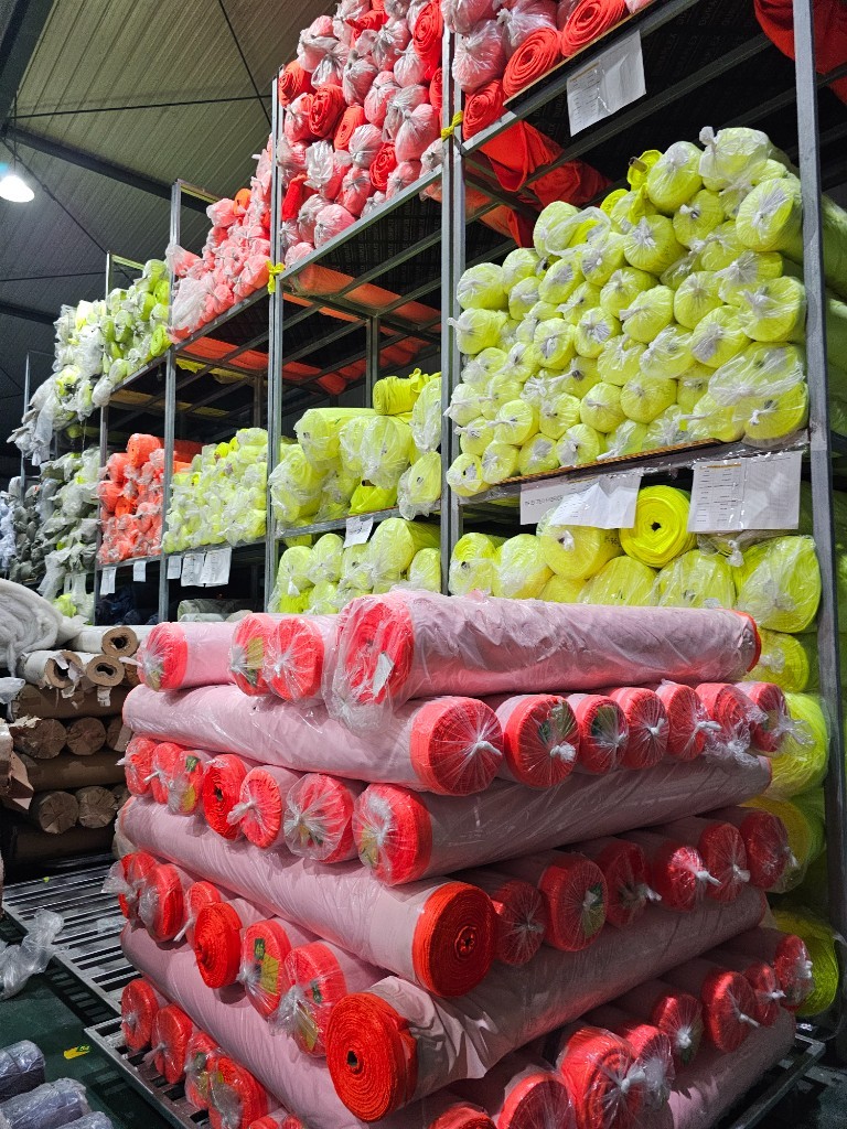 Stacks of fluorescent hi-vis fabric in yellow and orange, ready for cutting