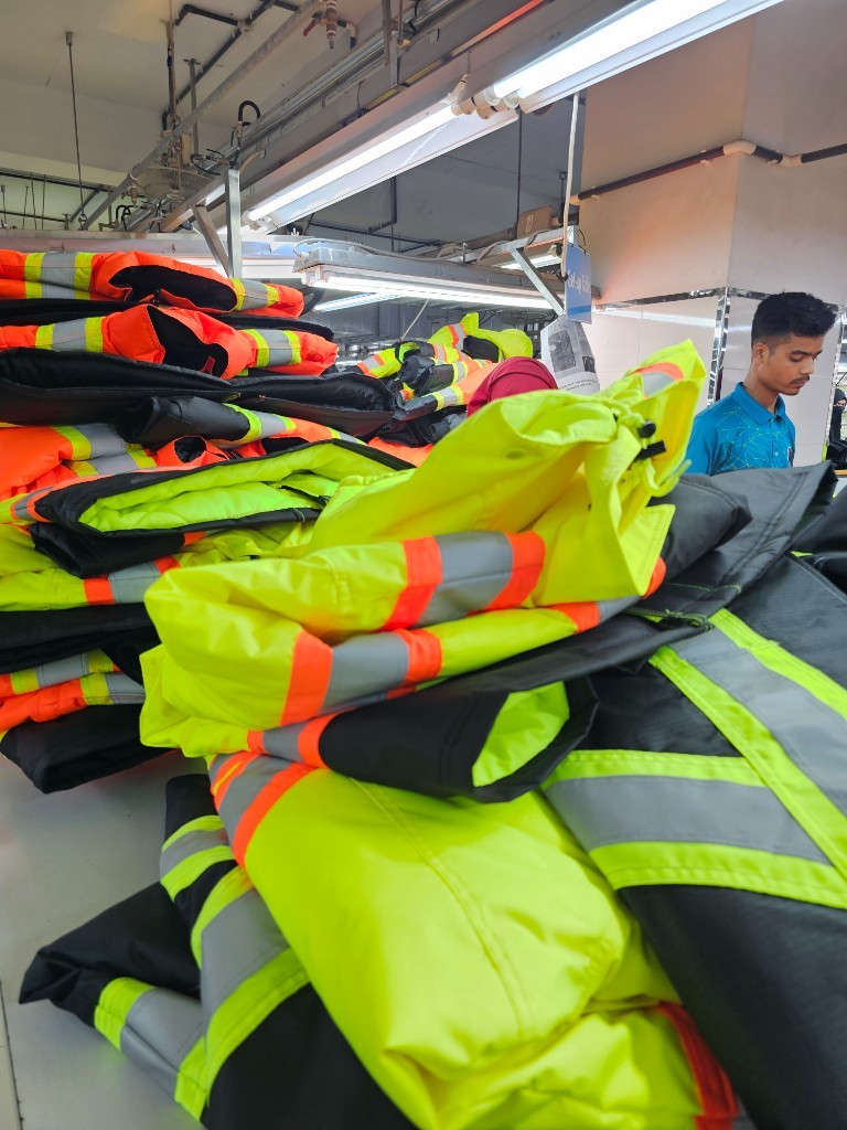 Rows of completed hi-vis safety jackets staged on a Bangladesh factory production floor ready for export