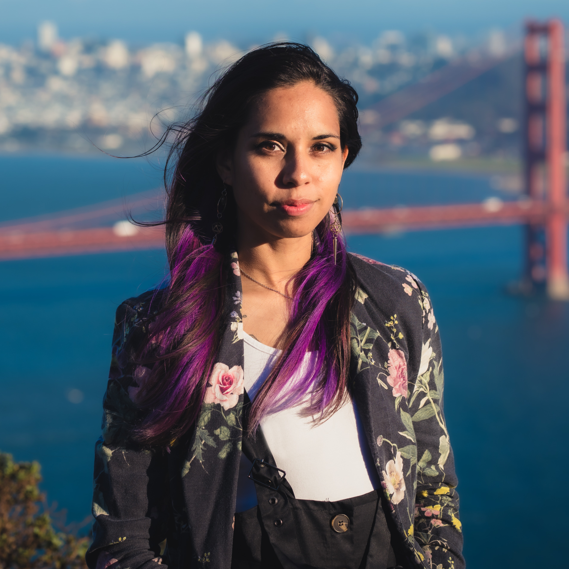 Woman with black and purple hair standing in front of the Golden Gate Bridge