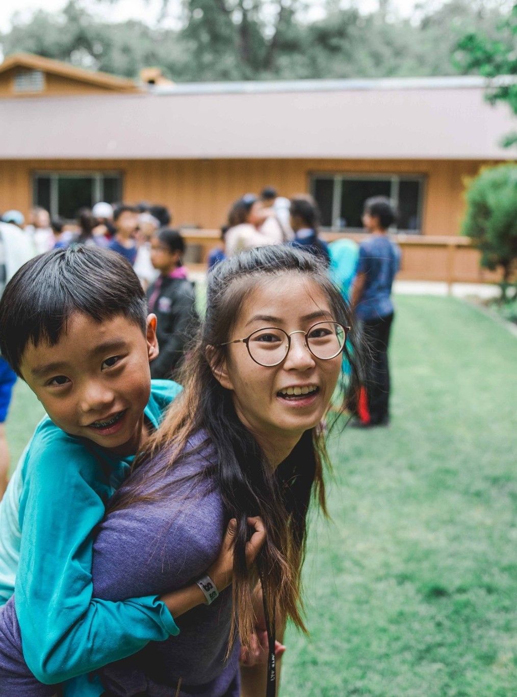 A LYF counselor giving a smiling camper a piggy-back ride