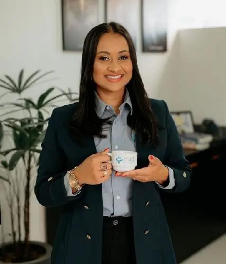 Mulher sorrindo segurando caneca da Mais Contábil em escritório