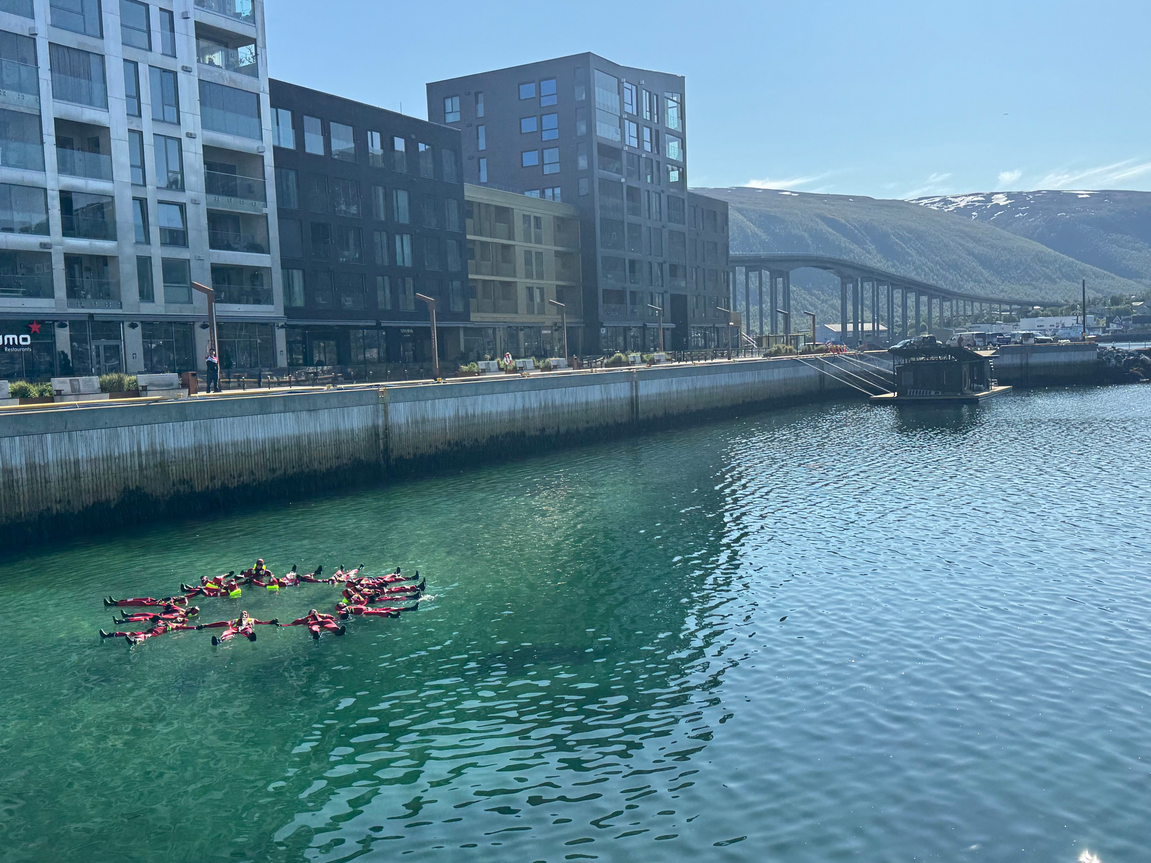 Guests floating together in survival suits during an Arctic floating adventure in Tromsø, Norway.