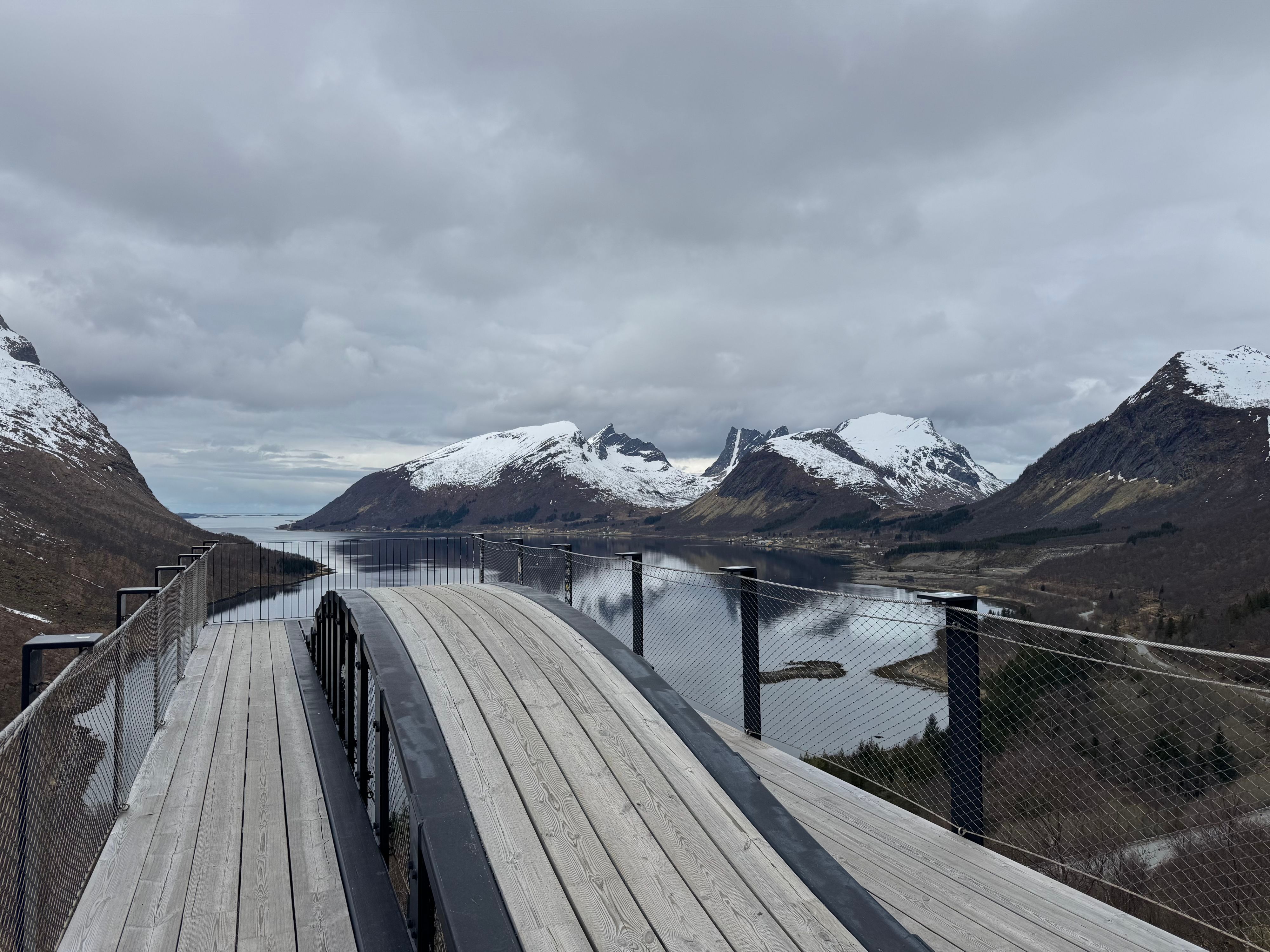 Utsiktsplattformen Bergsbotn med panoramautsikt over en stille fjord og snødekte fjell langs Nasjonal turistveg Senja i Nord-Norge.