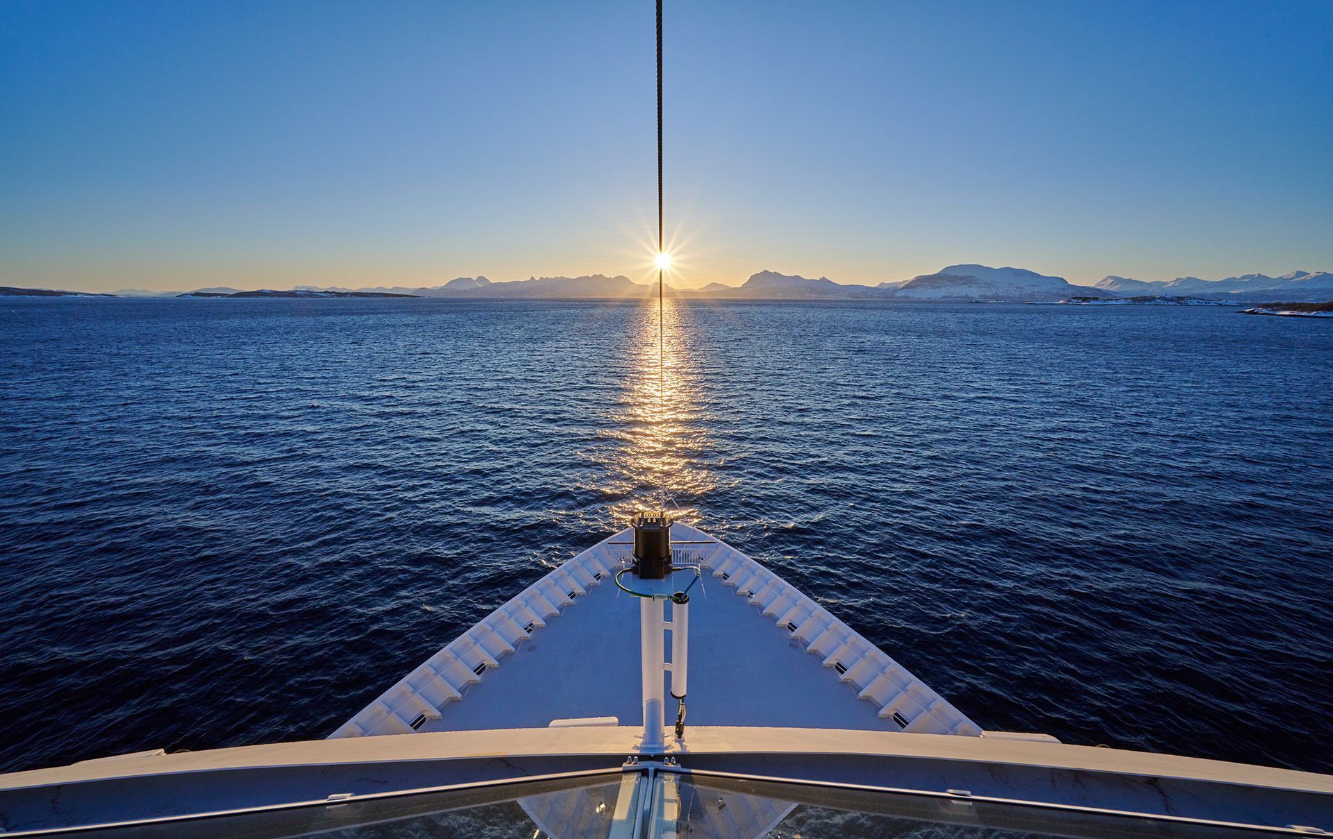 View from the ship's bow sailing through the narrow Risøyrenna channel at dusk