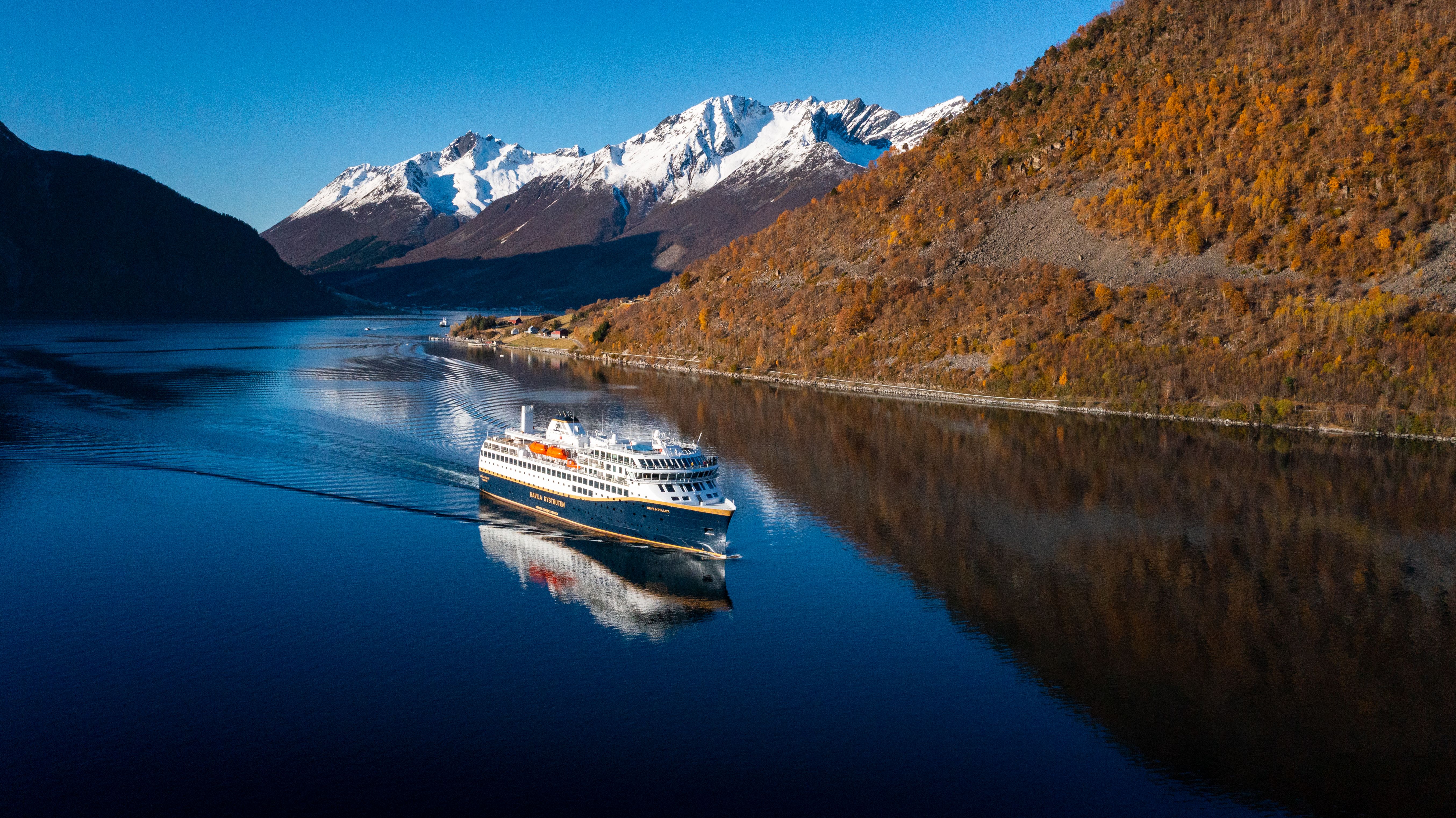 Havila-skip seiler gjennom den stille Hjørundfjorden, forbi høstløv og snødekte fjelltopper