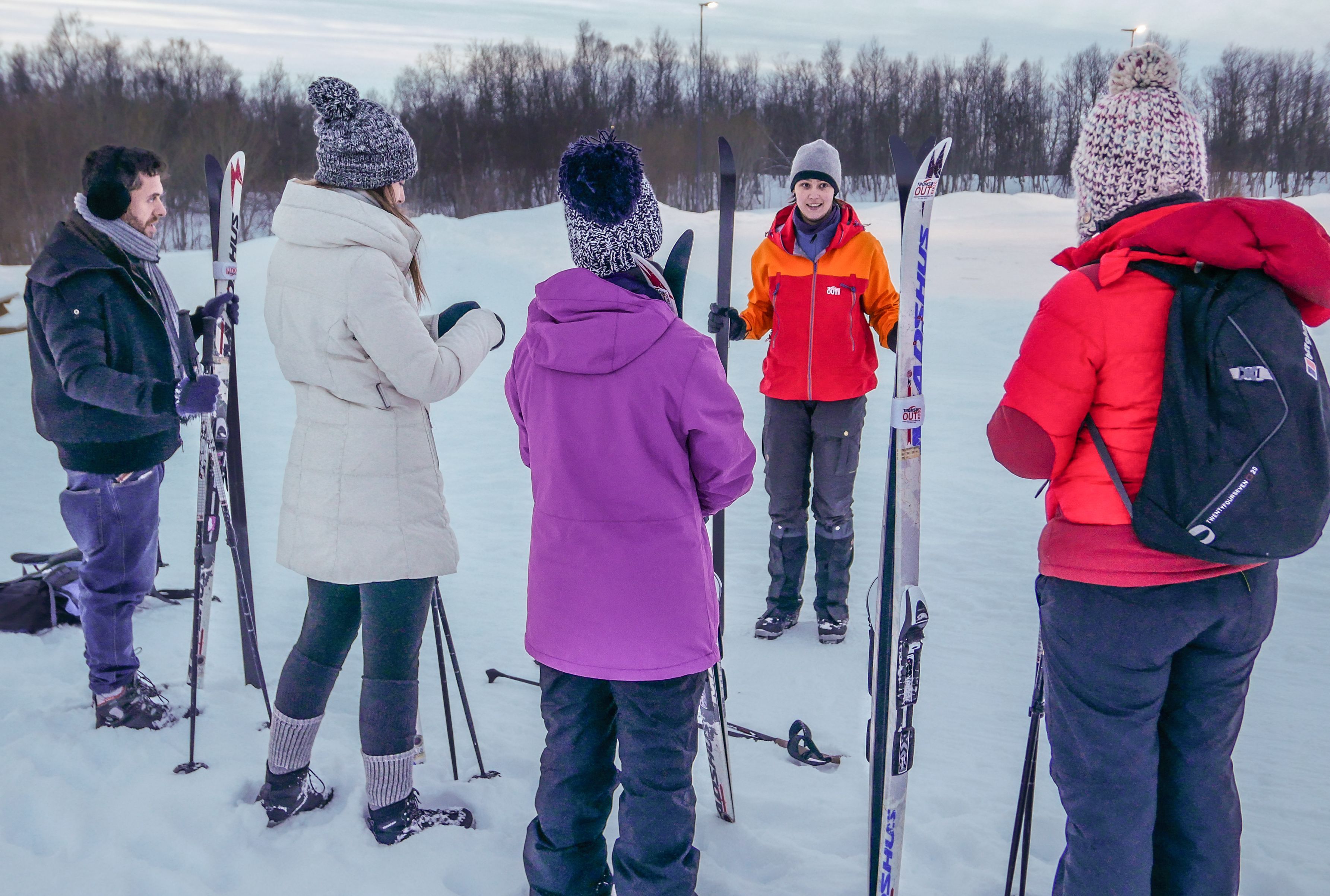 Gjester samles rundt en guide for en innførende langrennstime i Tromsø, der de lærer grunnleggende teknikker før de legger ut på preparerte, snødekte løyper.