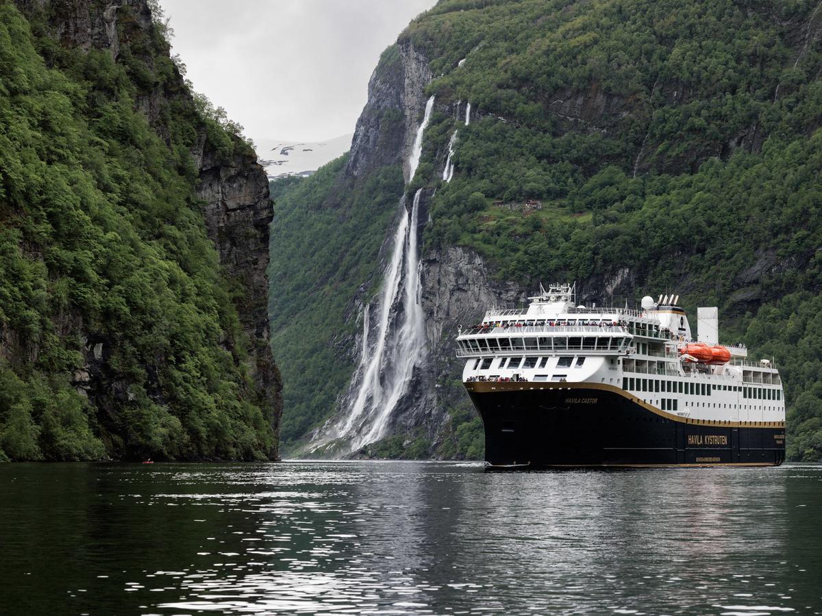 Cruise i Geirangerfjorden med en foss omgitt av bratte fjell