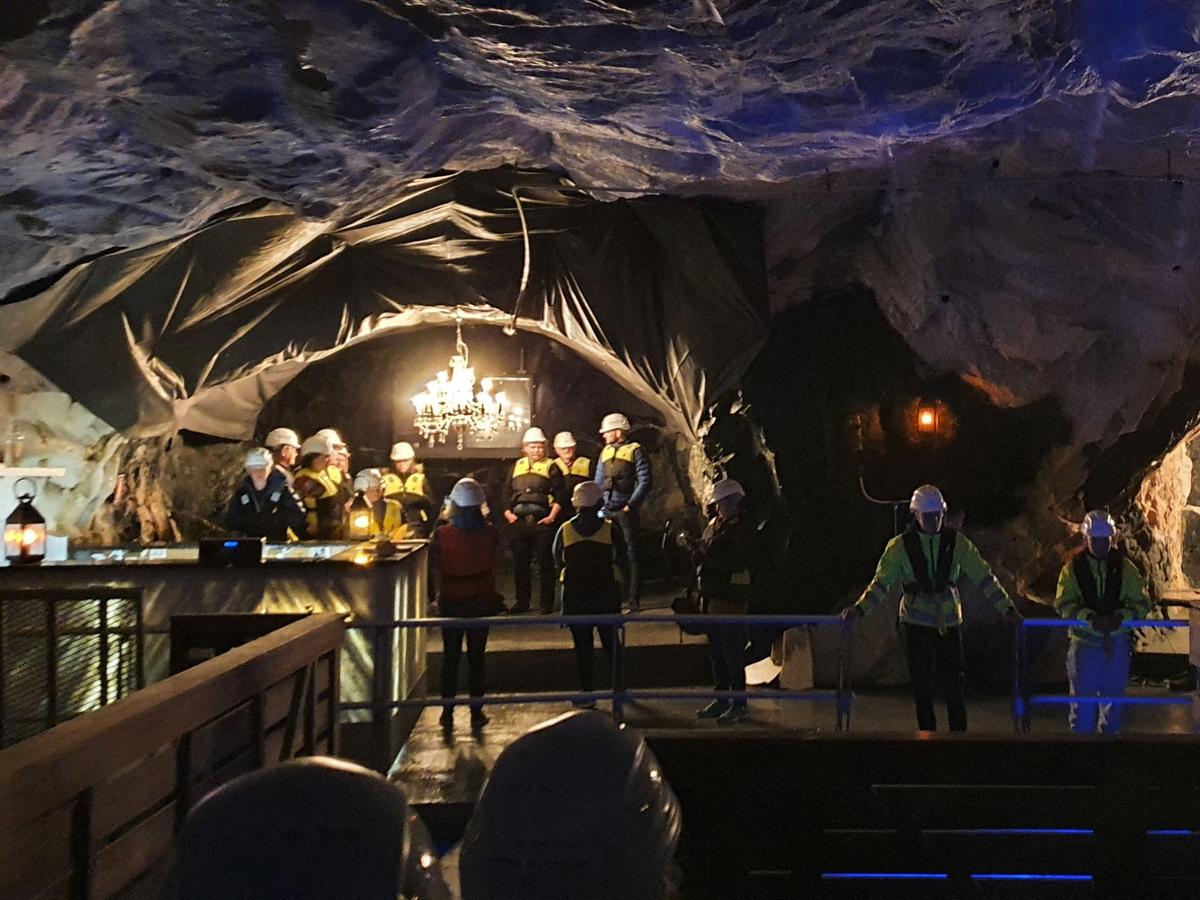 Guests wearing helmets explore the illuminated Bergtatt Marble Cave during an underground boat experience.