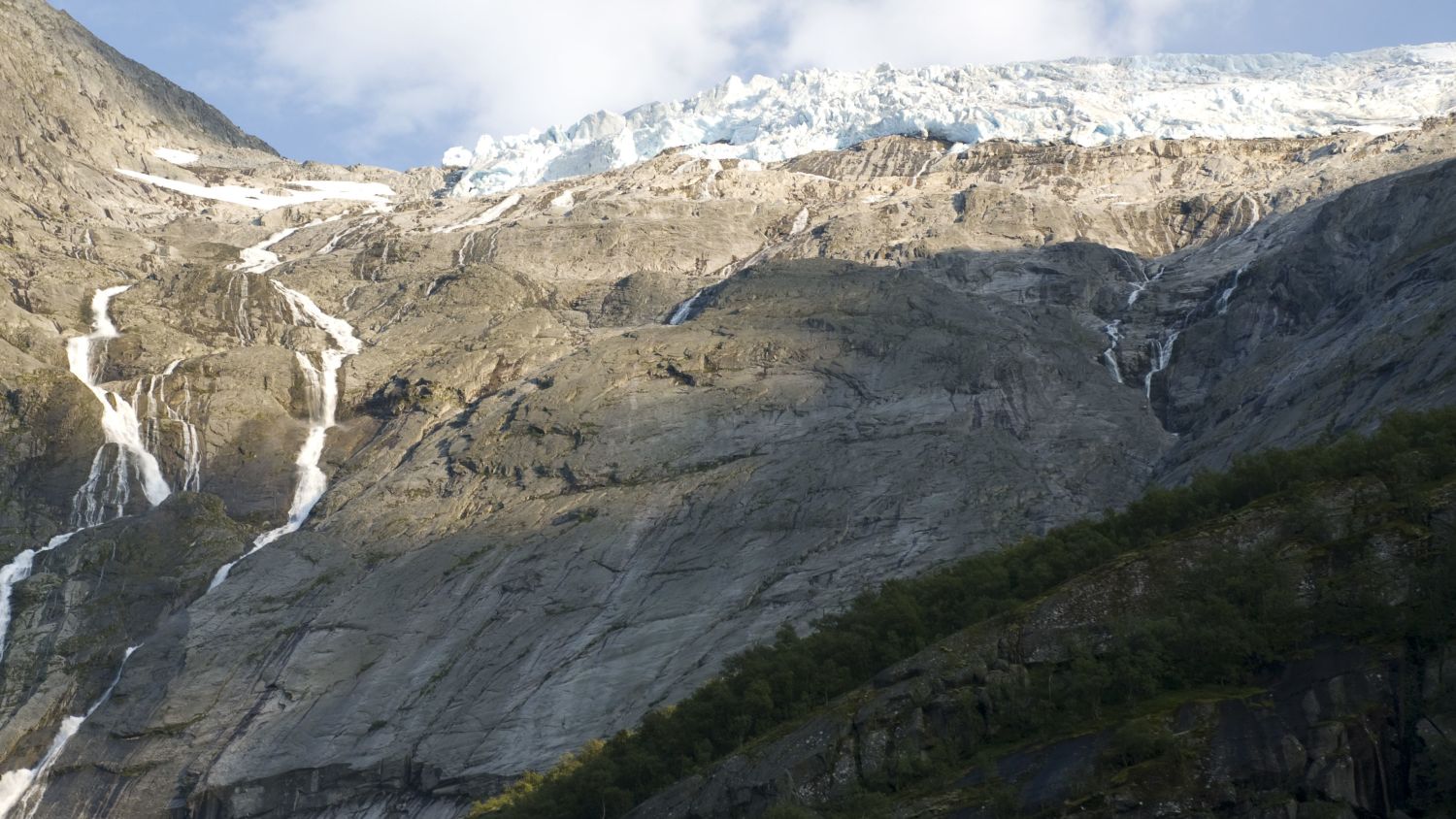 Panoramablick auf einen norwegischen Gletscher mit Wasserfällen, die über zerklüftete Berghänge hinabstürzen