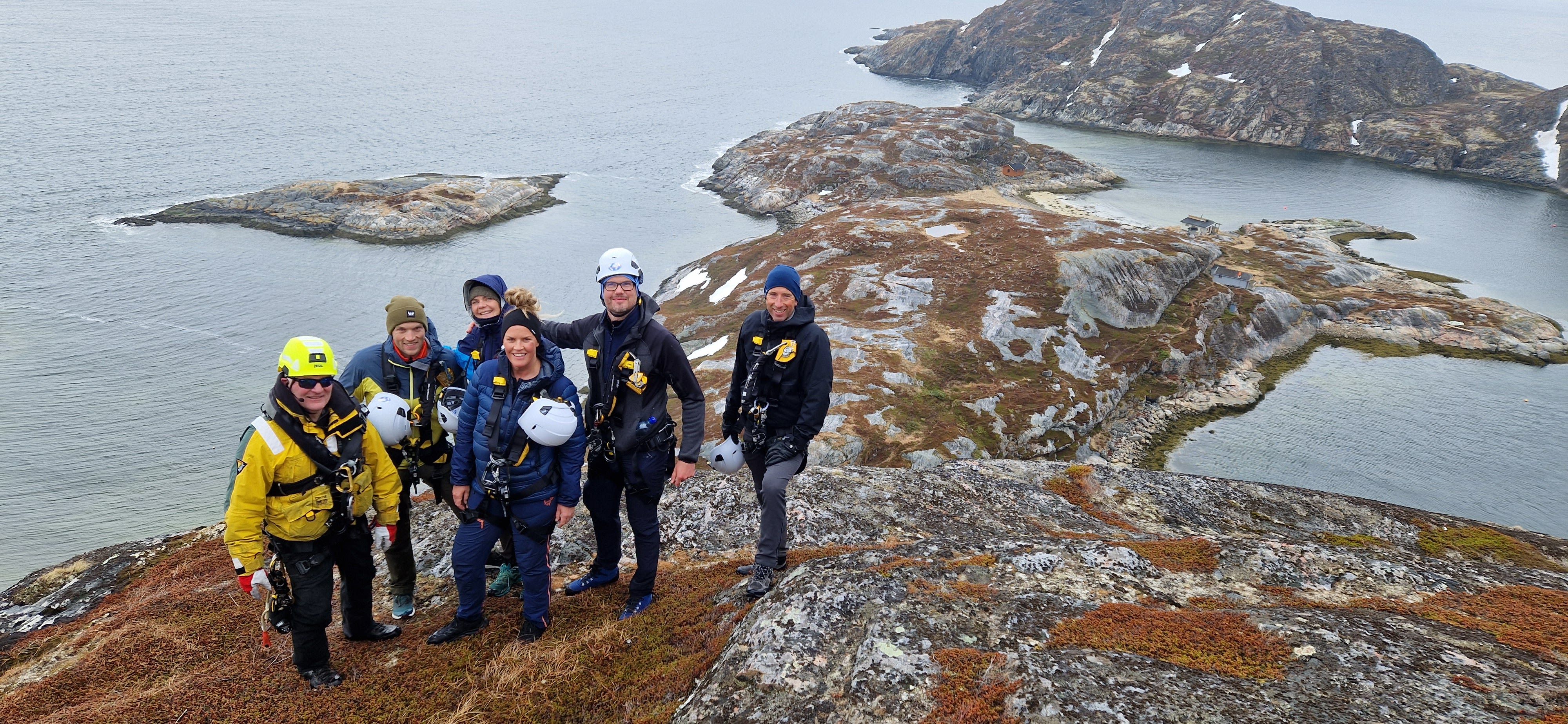 Group of participants at the Arctic Rappelling Route enjoying panoramic coastal views before the descent.