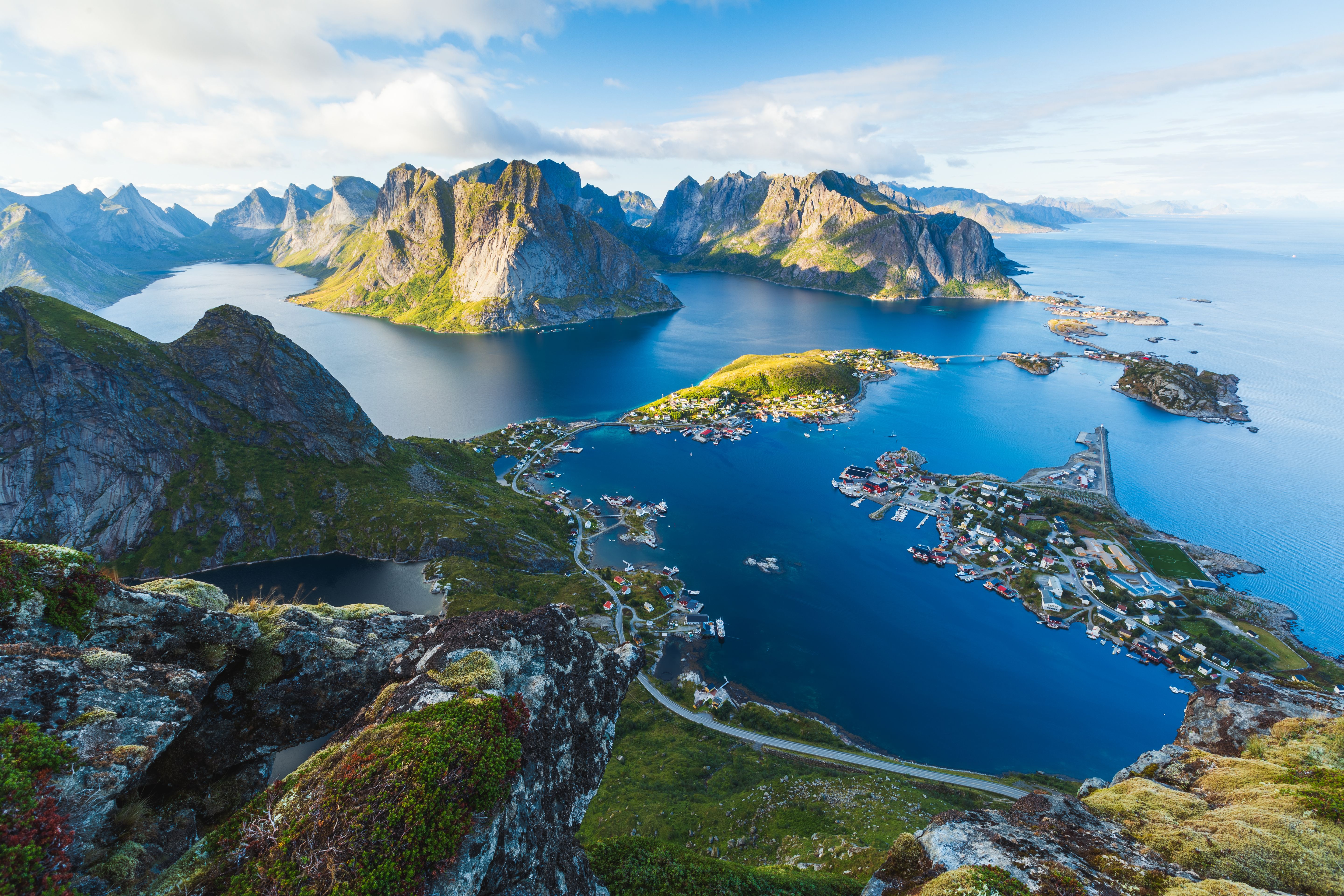 Aerial view of Reine in the Lofoten Islands, surrounded by dramatic mountains and blue fjords.