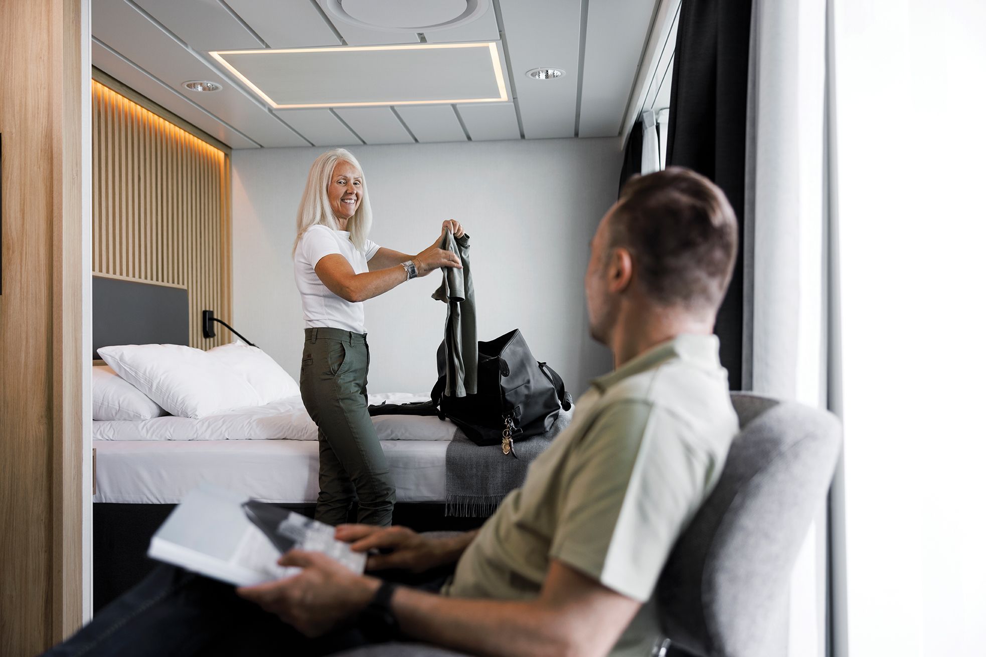 Guests relaxing in a spacious, modern cabin aboard a Havila Voyages ship.