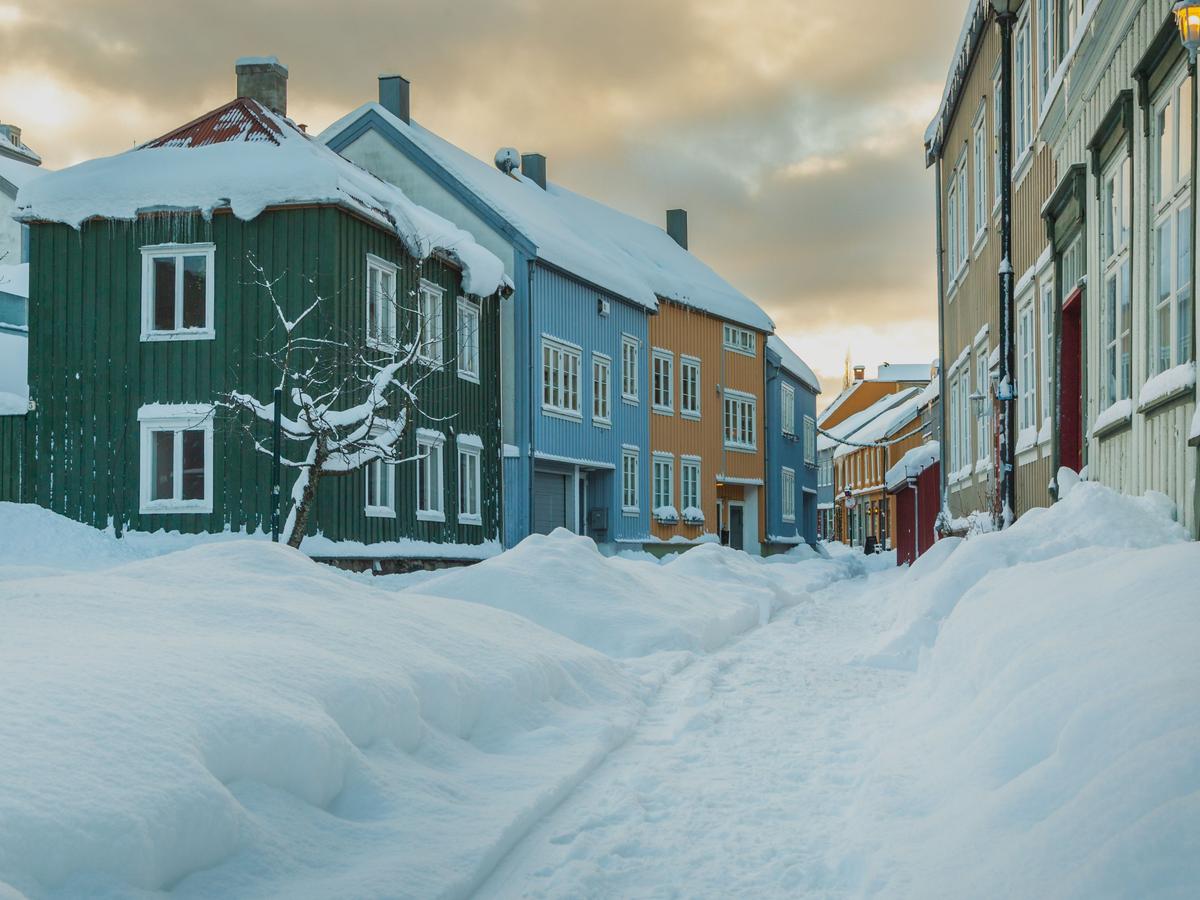 Fargerike trehus langs en snødekt gate i Trondheim om vinteren.