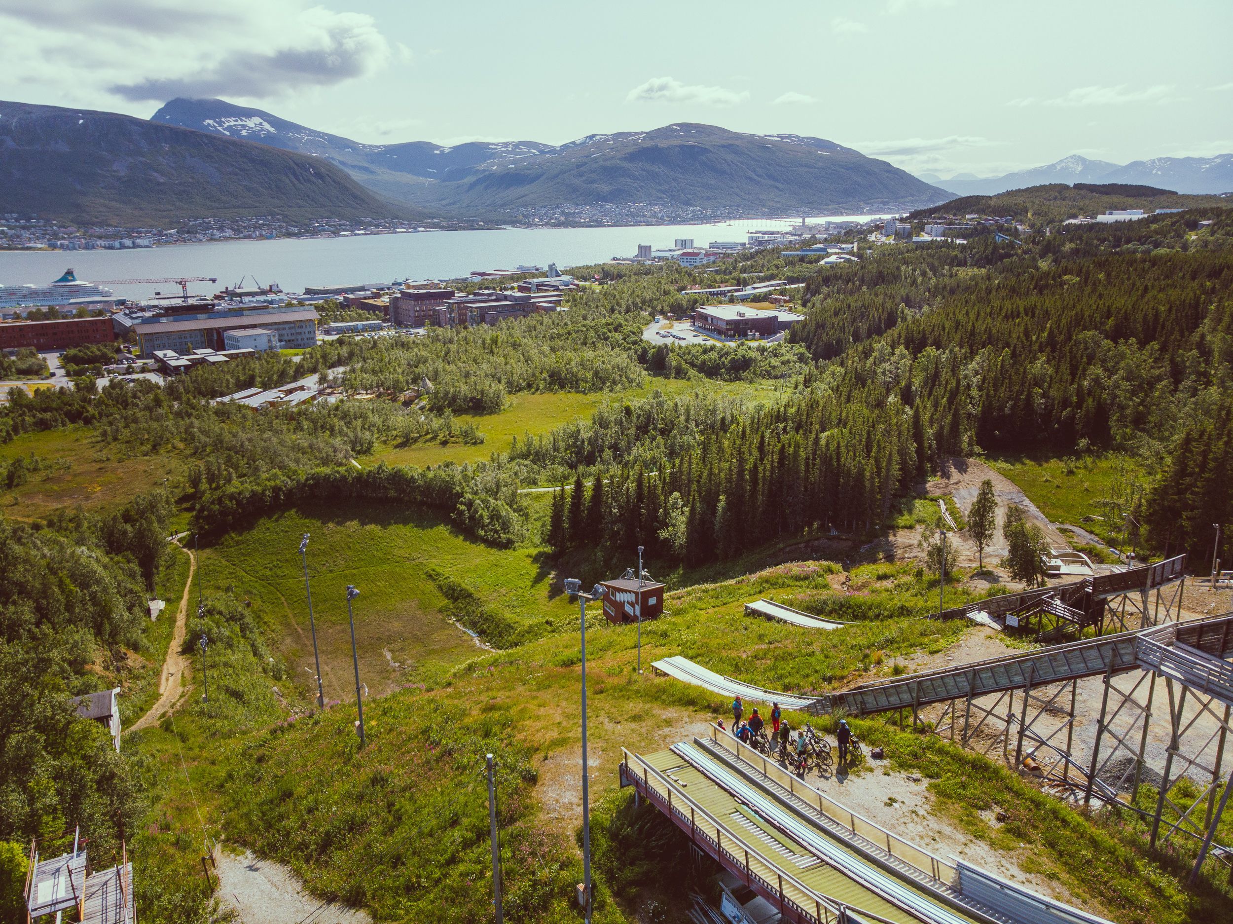 Panoramautsikt over skihoppene i Tromsø og skifjordene med syklister på en guidet elsykkeltur med utsikt over byen.