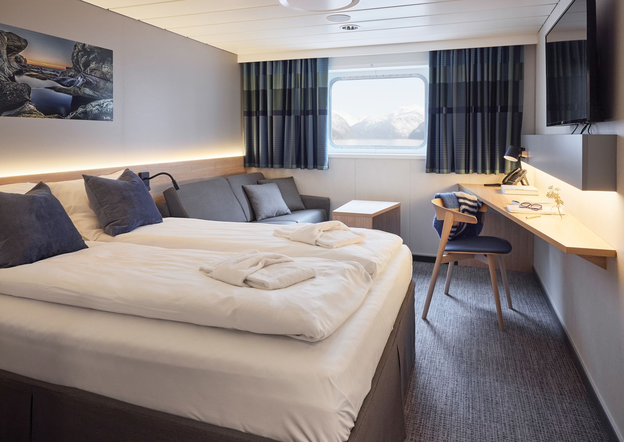 Sjøutsikt Superior dobbeltlugar med dobbeltseng, sofa, skrivebord, TV og stort vindu med utsikt over havet.