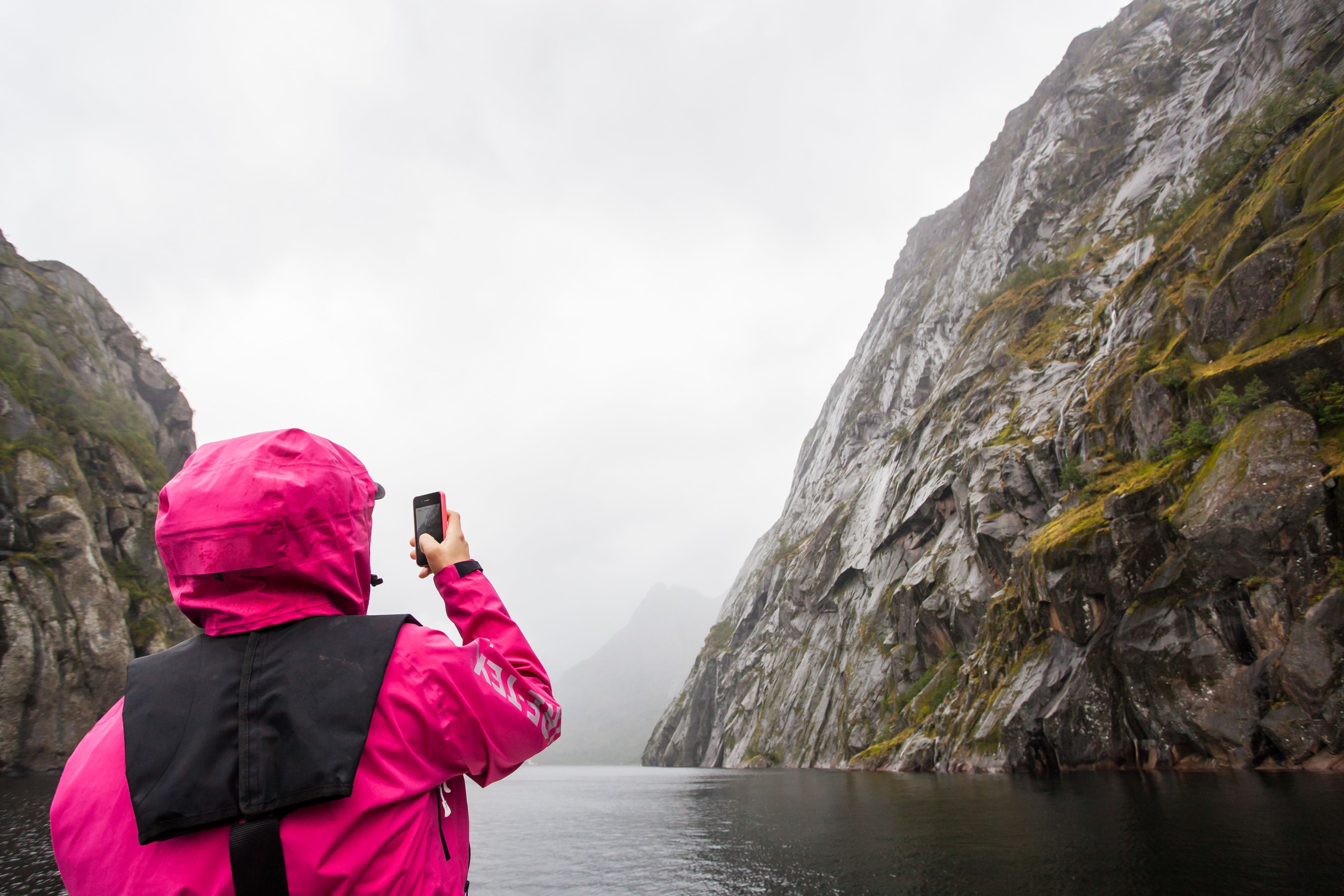 Person som tar ett foto i Trollfjorden under en dimmig dag