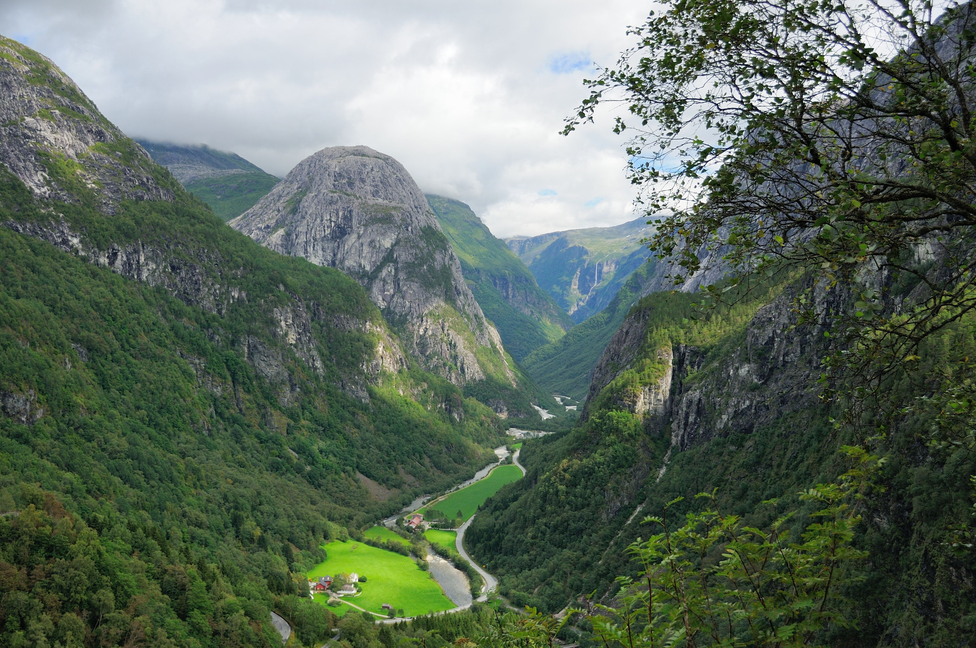 Panoramablick auf das Nærøydalen-Tal mit üppigen Wäldern, einem sich schlängelnden Fluss und steilen Felsklippen.