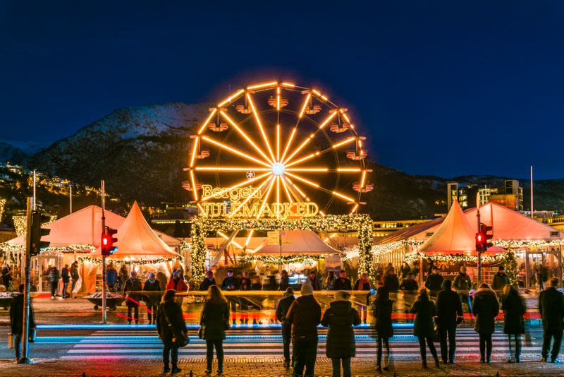 Weihnachtsmarkt im Dezember mit einem leuchtenden Riesenrad, festlichen Ständen und Besuchern, die die weihnachtliche Atmosphäre in Norwegen genießen