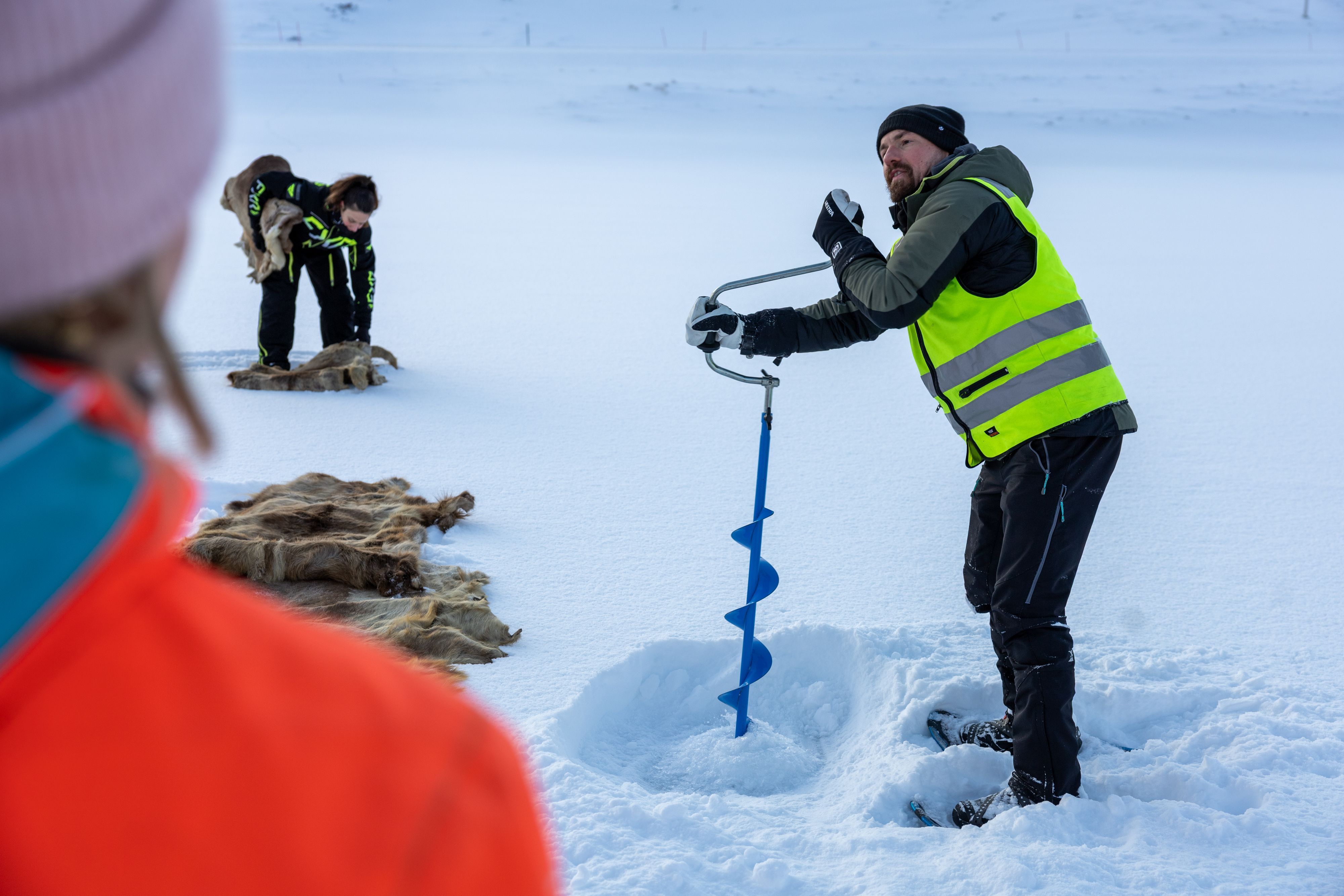 Guide borrar ett pimpelhål under en snöskovandring i arktiska Honningsvåg.