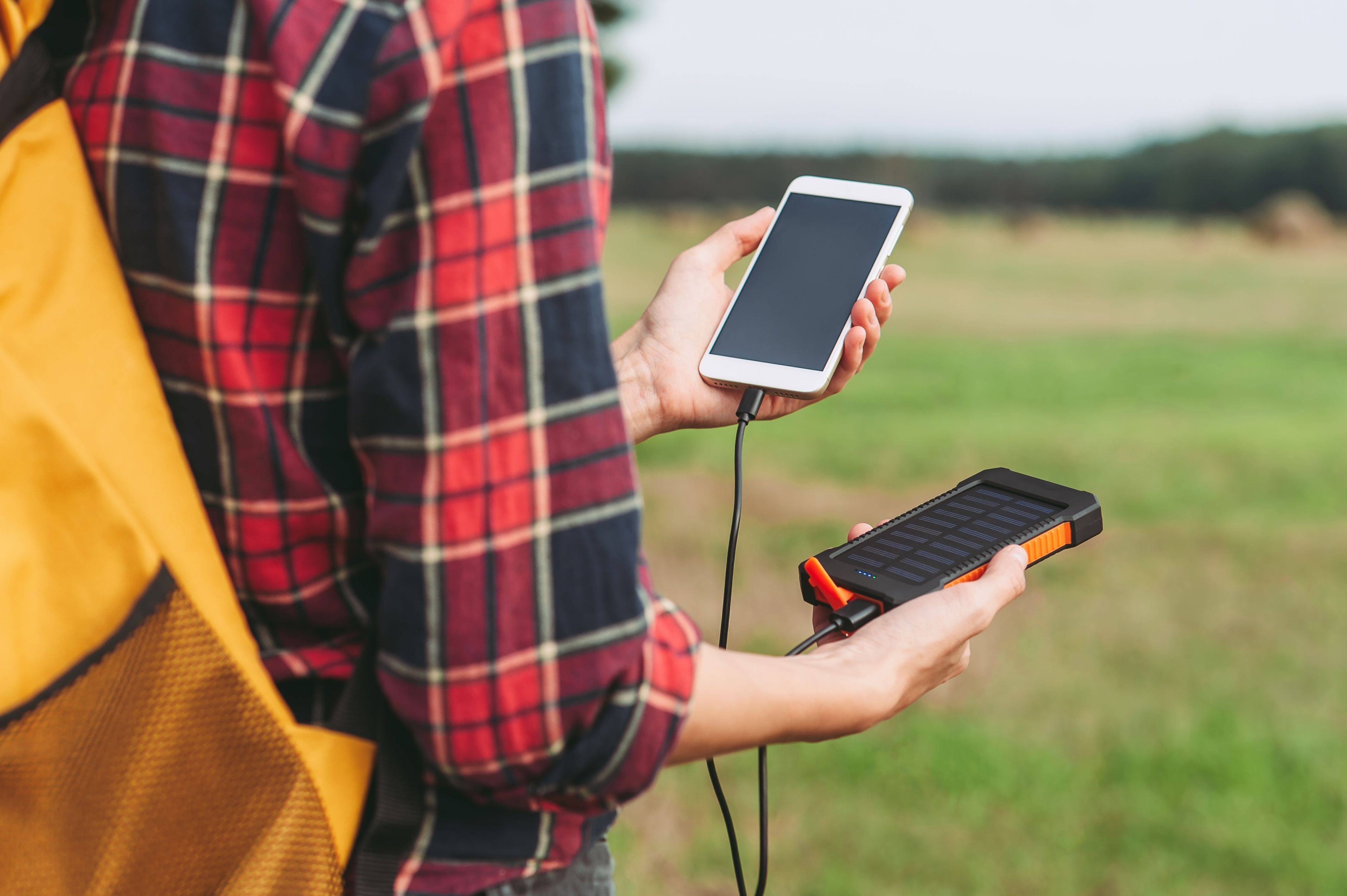 person som holder telefon og powerbank i hendene