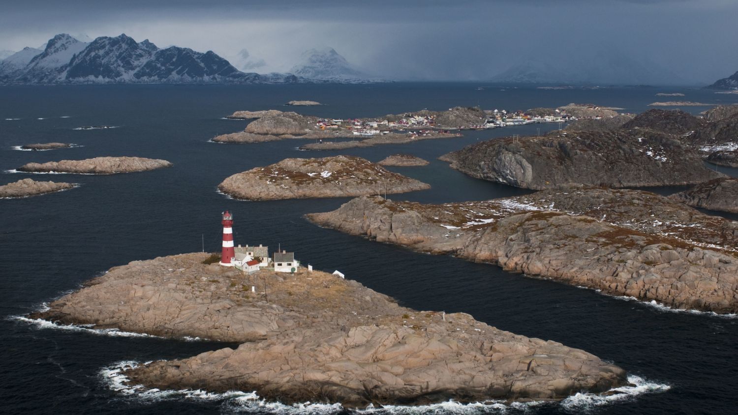 Traditional lighthouse in the Lofoten Islands, Norway, standing along a rugged Arctic coastline with dramatic mountains, pristine waters, and breathtaking coastal scenery