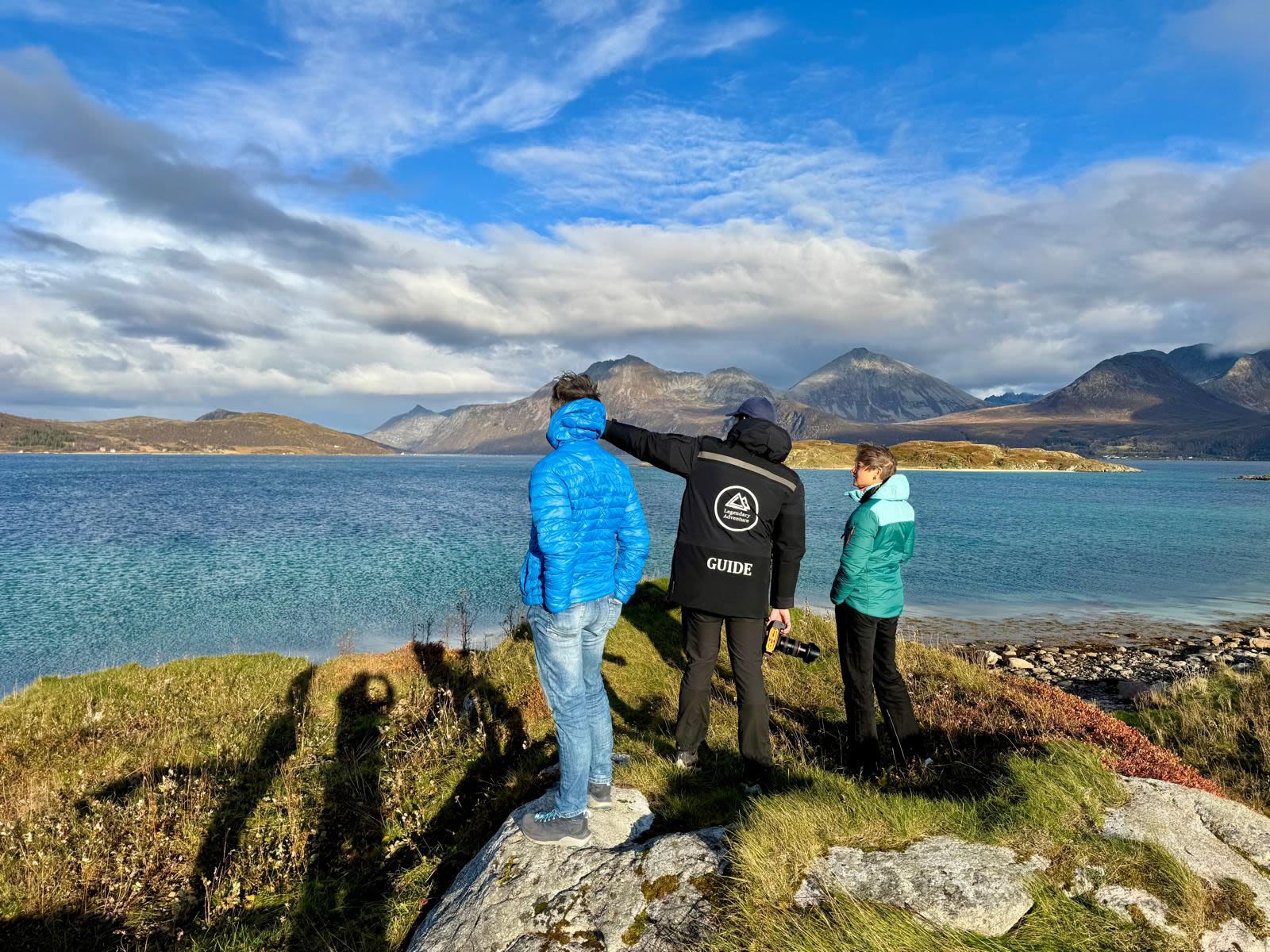 Guide som viser gjester det spektakulære kyst- og fjellandskapet fra et utsiktspunkt langs Nasjonal turistveg Senja i Nord-Norge.