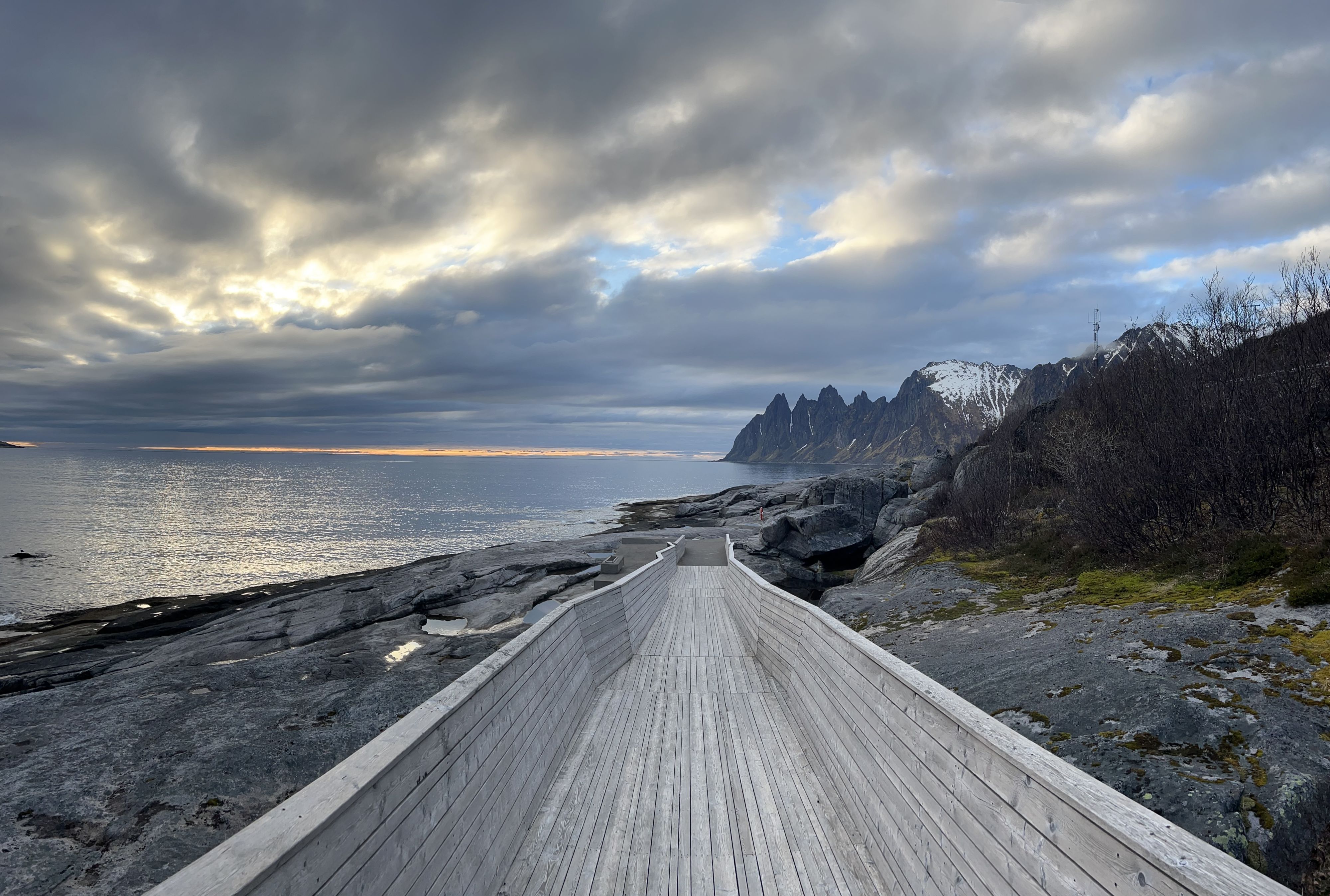 Tungeneset gangvei som fører over glatte svaberg mot de dramatiske Okshornan-toppene langs Nasjonal turistveg Senja.