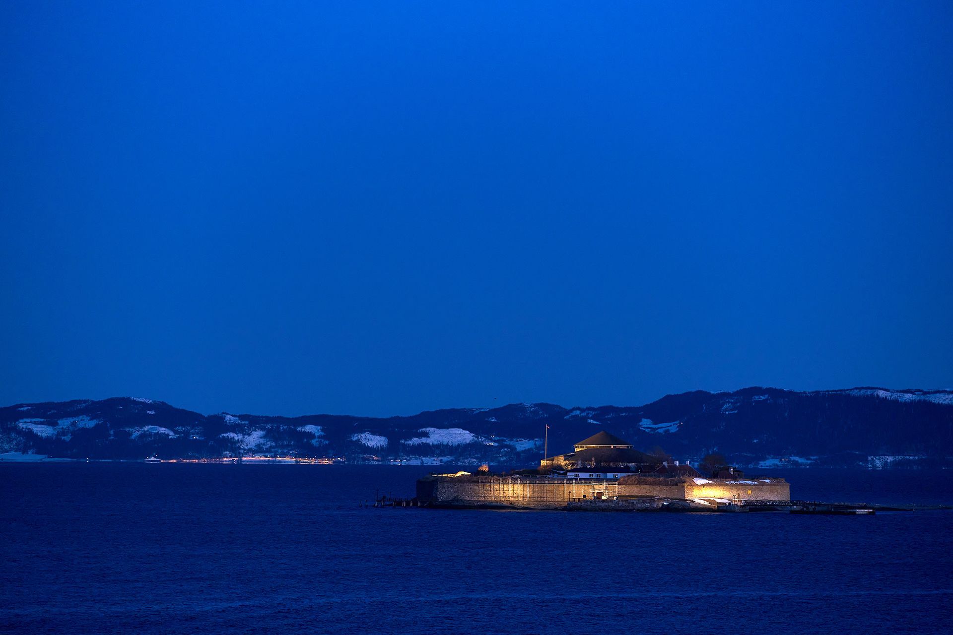 Munkholmen island fortress lit up in the Trondheim fjord at blue hour