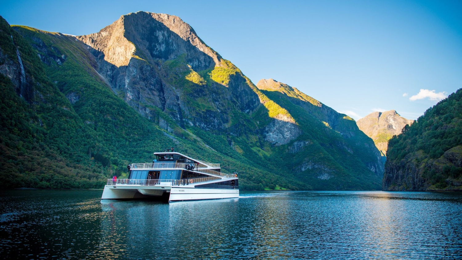 Null-Emissions-Fähre mit Batteriebetrieb, die durch den Nærøyfjord fährt, umgeben von hoch aufragenden Bergen und kristallklarem Wasser im UNESCO-Weltnaturerbefjord in Westnorwegen.