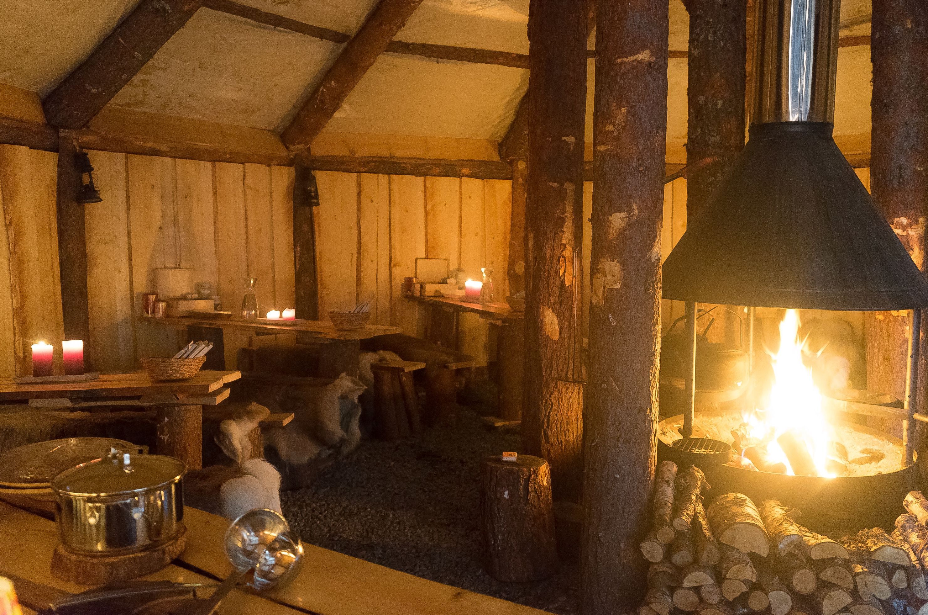 Interior of a traditional Sámi goahti with a fireplace and rustic wooden seating in Northern Norway