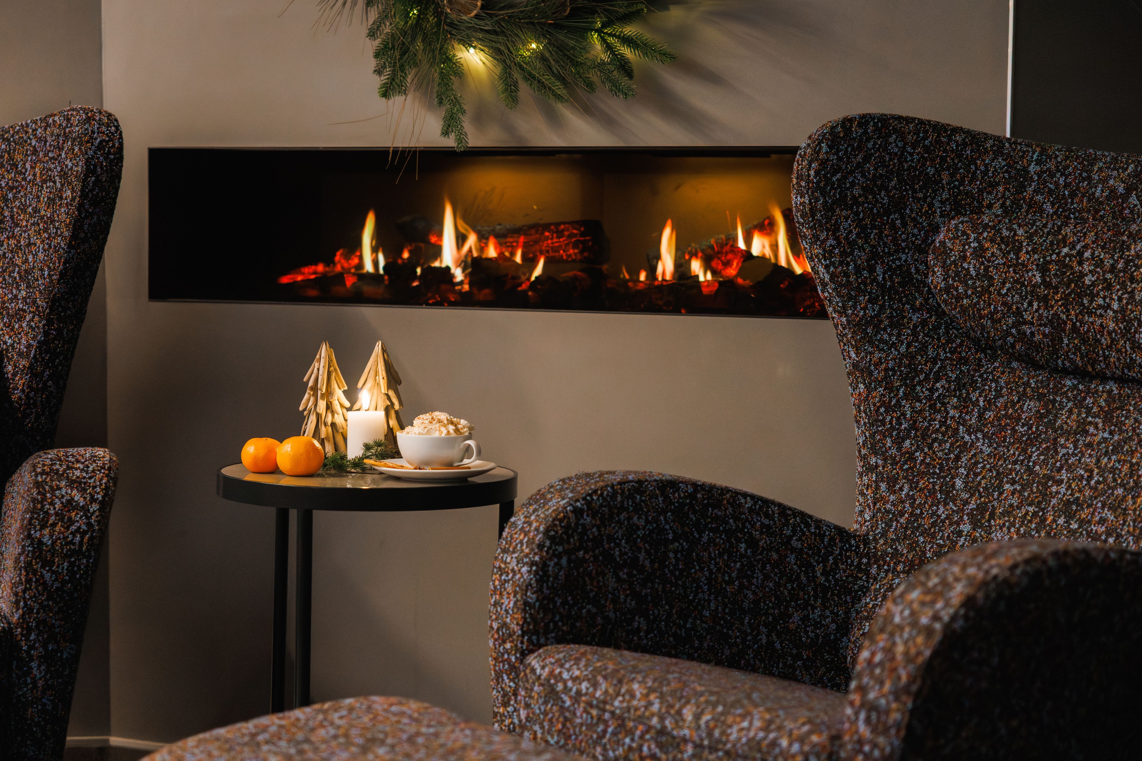 Gemütliche Lounge mit Kamin, heißer Schokolade und festlicher Dekoration an Bord einer norwegischen Küstenkreuzfahrt zu Weihnachten