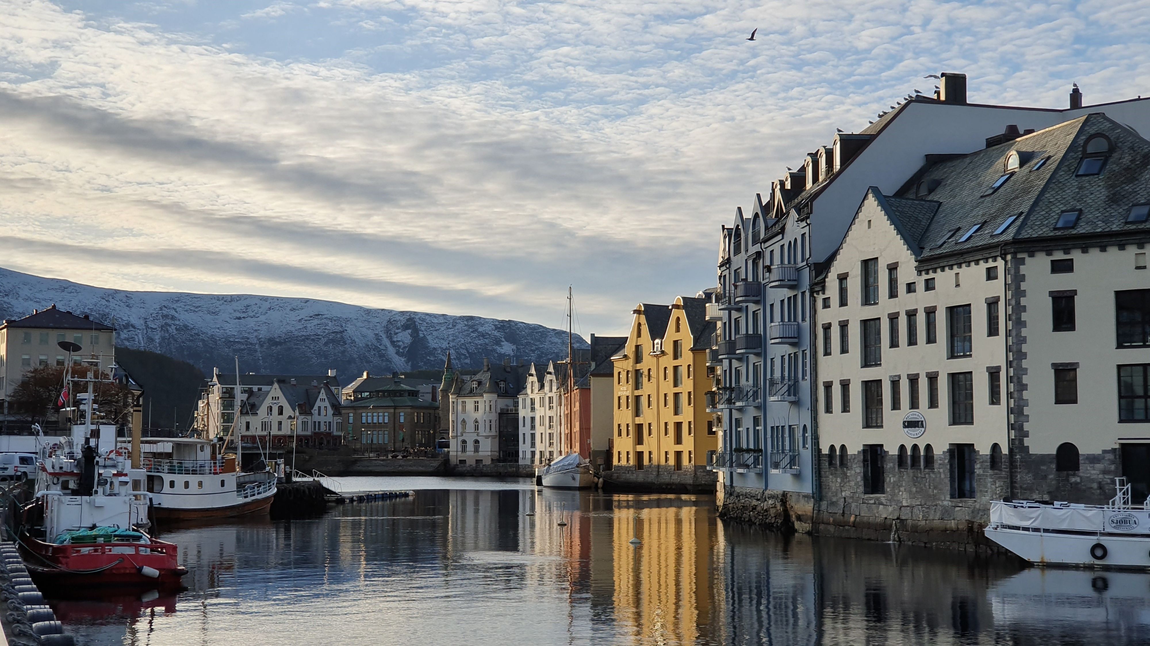 Jugendstilgebäude spiegeln sich im Hafen Brosundet in Ålesund, mit vertäuten Booten