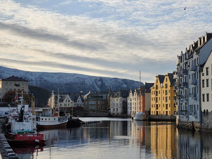 Jugendstilgebäude spiegeln sich im Hafen Brosundet in Ålesund, mit vertäuten Booten