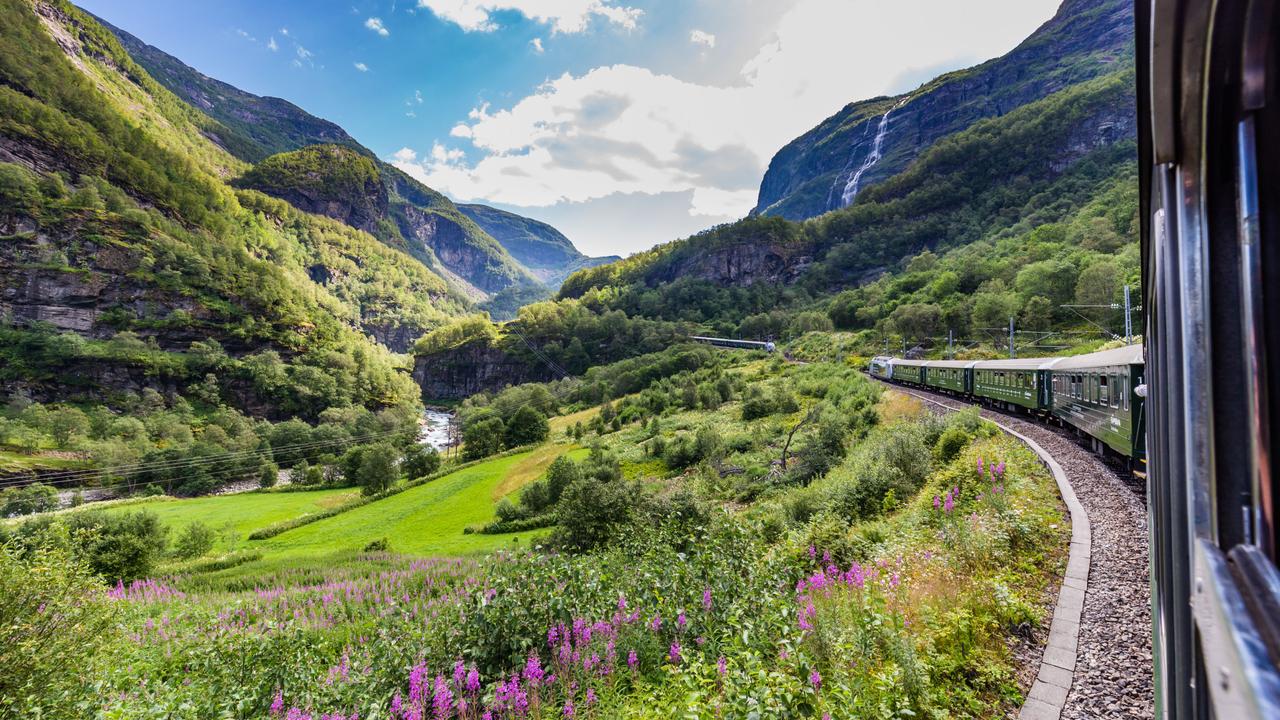 Die Flåm-Bahn schlängelt sich durch ein üppiges Bergtal, vorbei an Wasserfällen, Wildblumen und dramatischen Klippen, auf einer der landschaftlich schönsten Zugstrecken Norwegens.