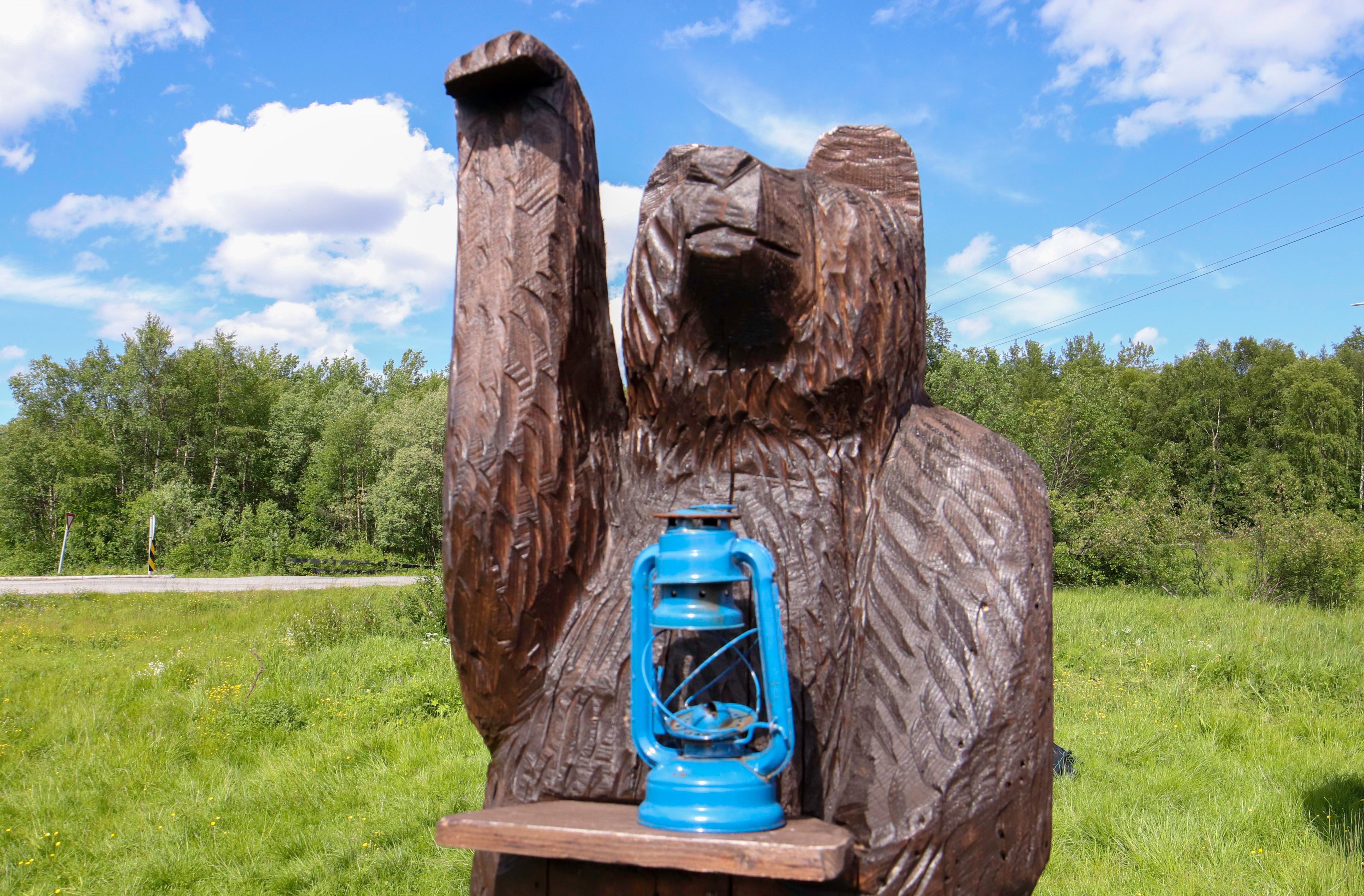 Wooden brown bear carving with a blue lantern in Pasvik Valley near Kirkenes, Northern Norway.