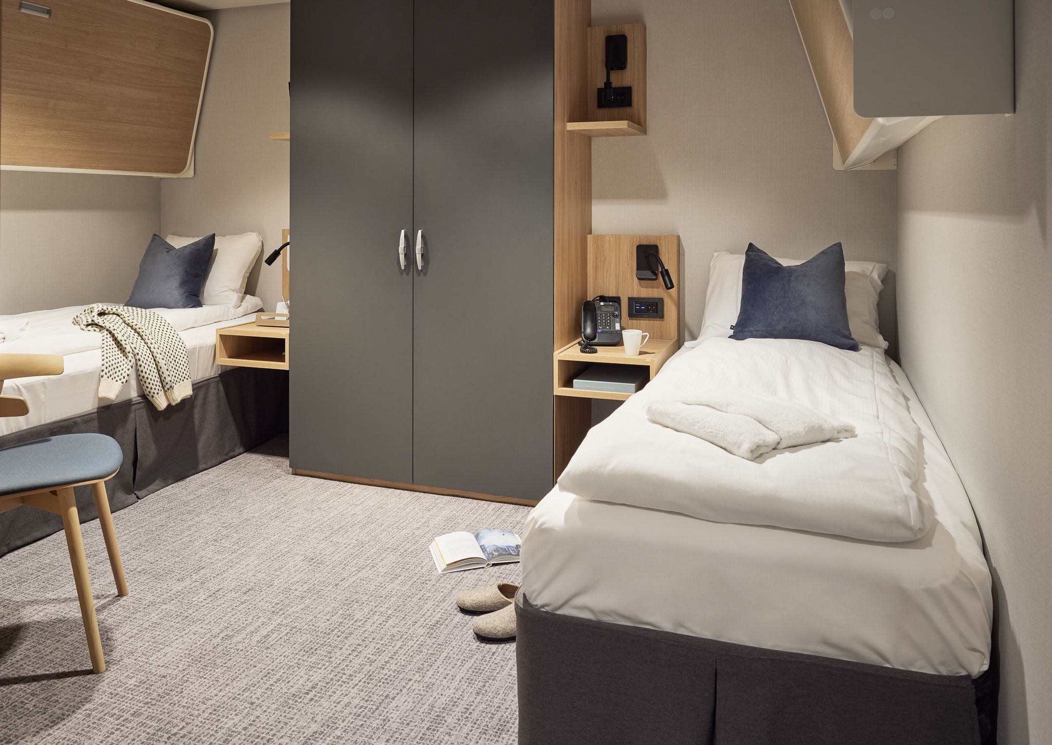 Barrierefreie Innenkabine auf einem Kreuzfahrtschiff mit zwei Einzelbetten, großzügigem Grundriss, Kleiderschrank, Stauraum am Bett und moderner Einrichtung.