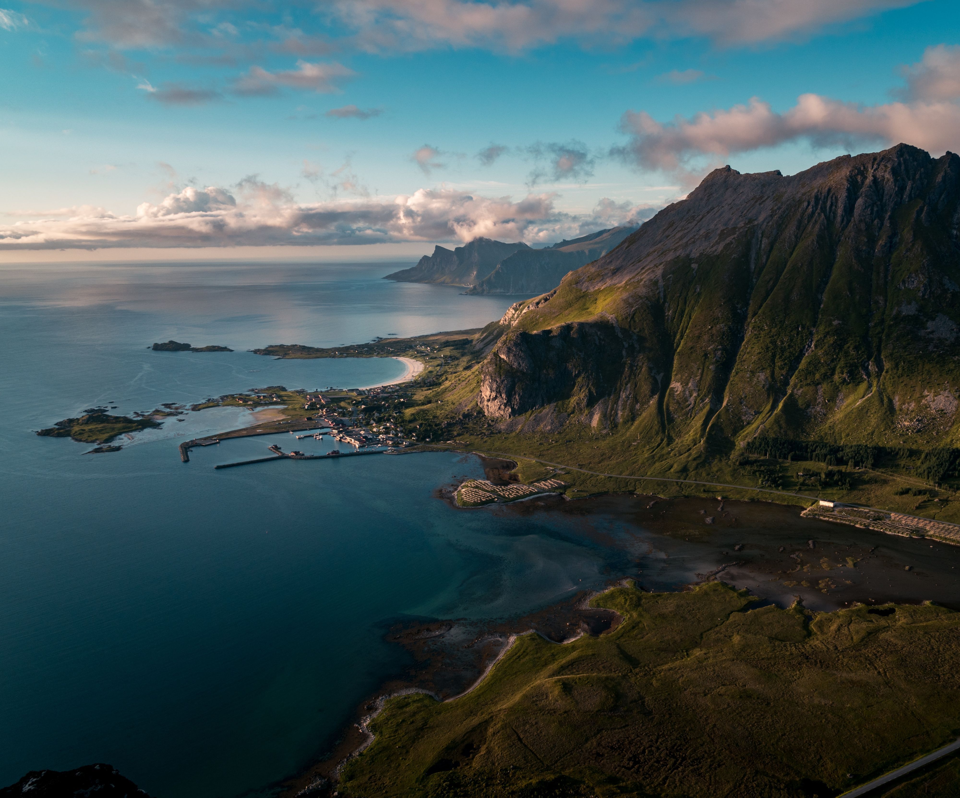 Aerial view of Lofoten’s dramatic coastline with mountains, beaches, and fishing village.