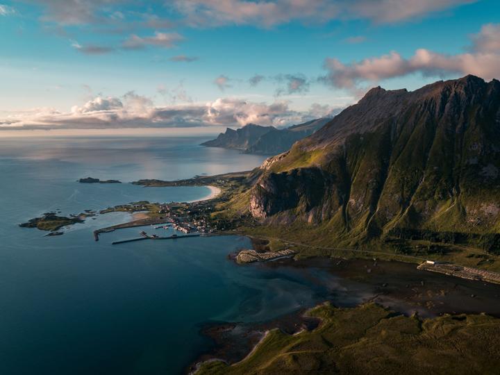Aerial view of Lofoten’s dramatic coastline with mountains, beaches, and fishing village.