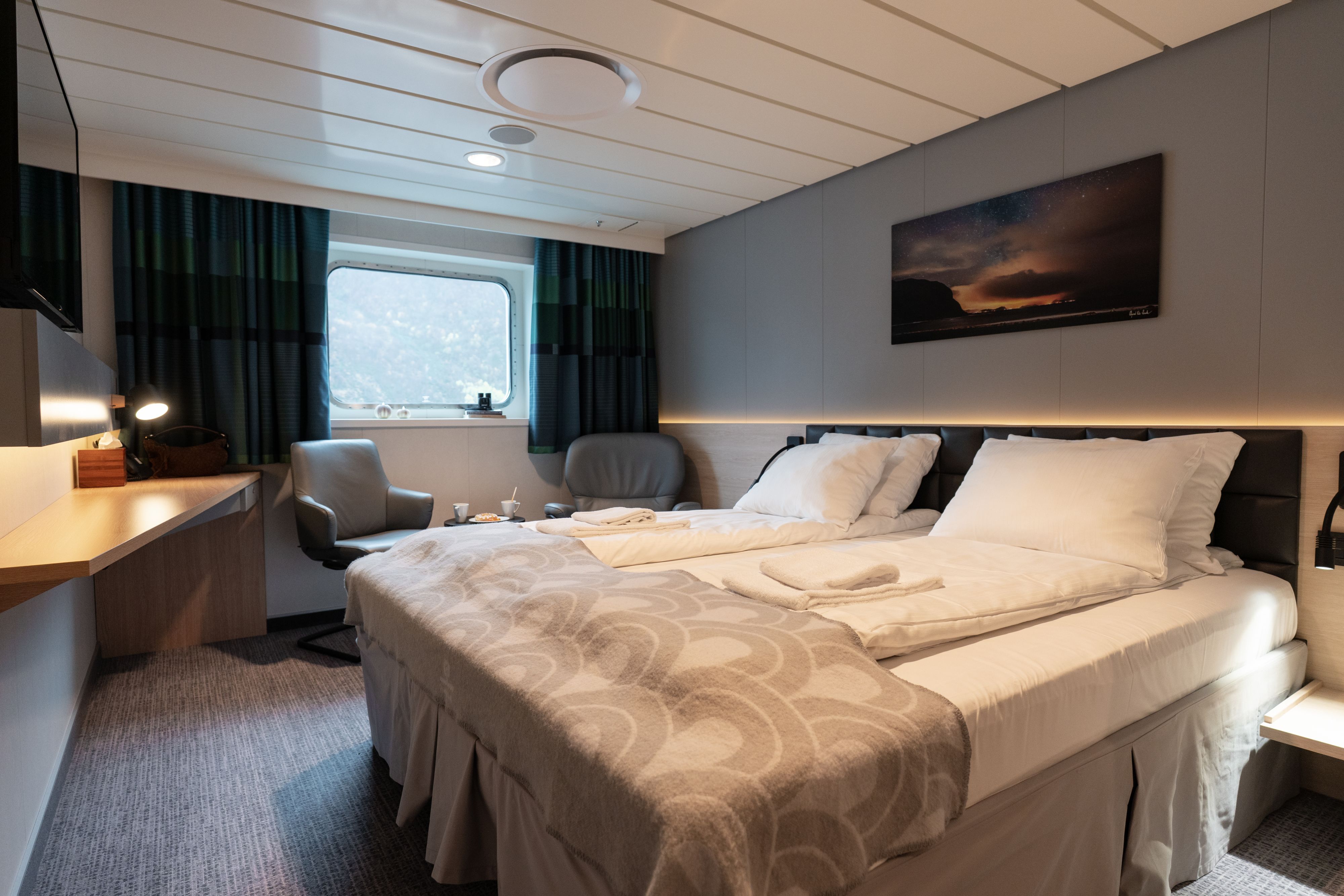 Superior-Kreuzfahrtkabine Seaview mit Kingsize-Bett, Meerblick, Schreibtisch, Sitzecke und modernen Annehmlichkeiten.