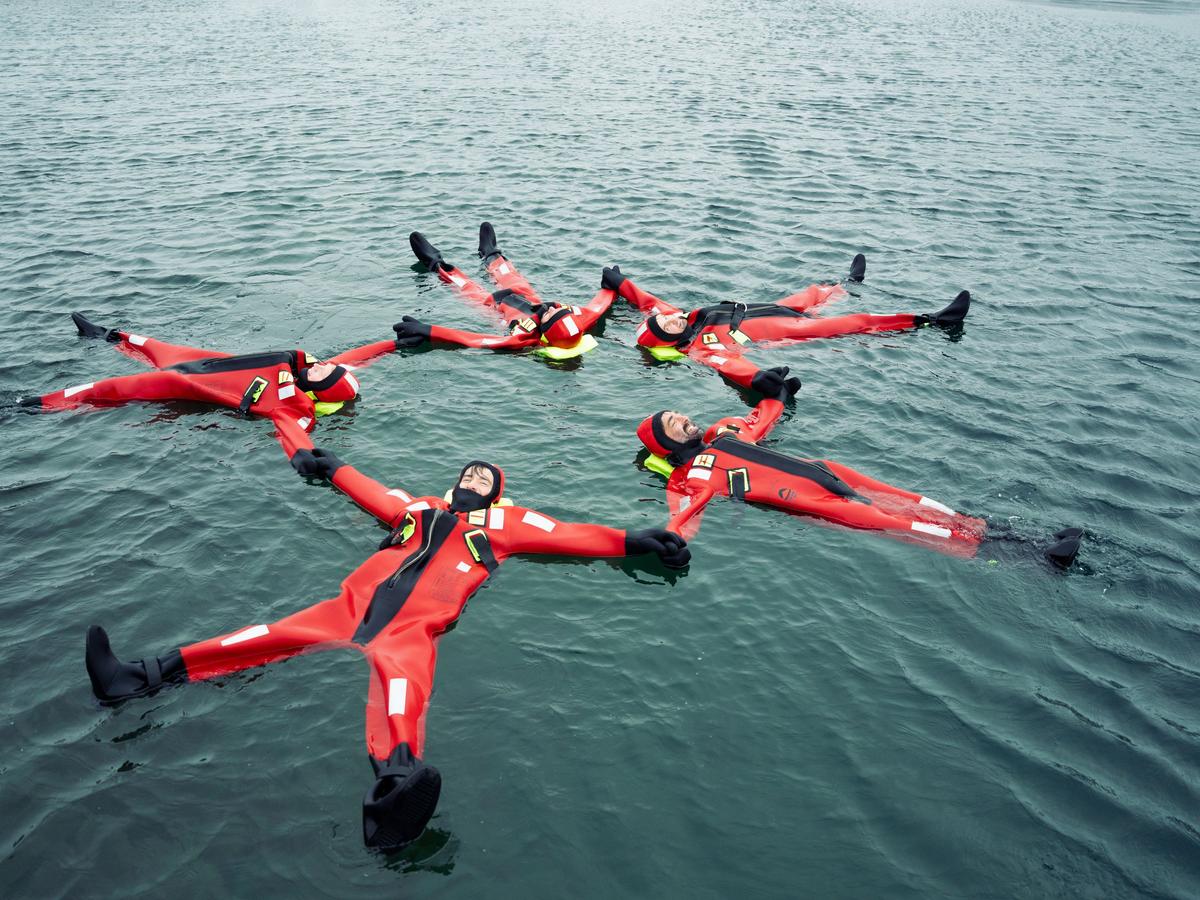 People wearing red survival suits floating together in the Arctic waters of Tromsø.