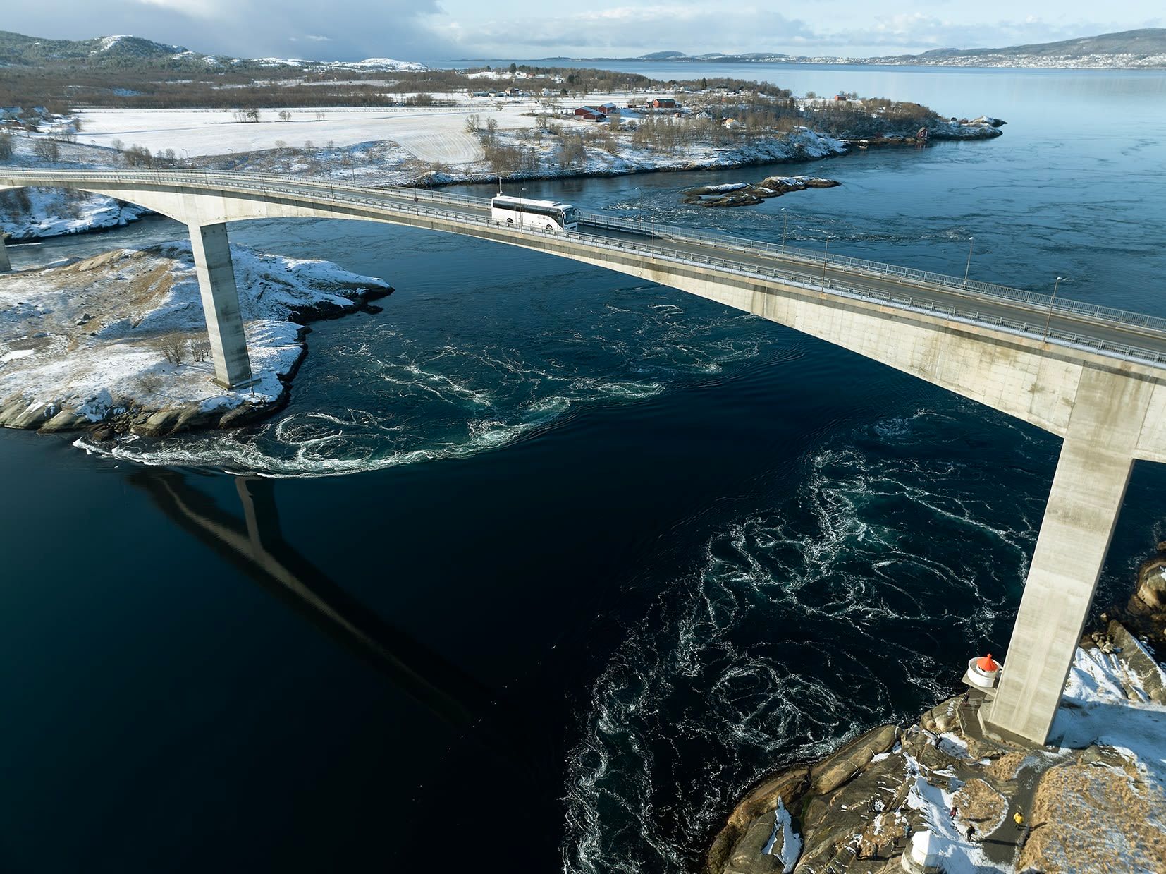 Saltstraumen veibro som krysser lyse turkise tidevannsstrømmer sett ovenfra nær Bodø, Norge